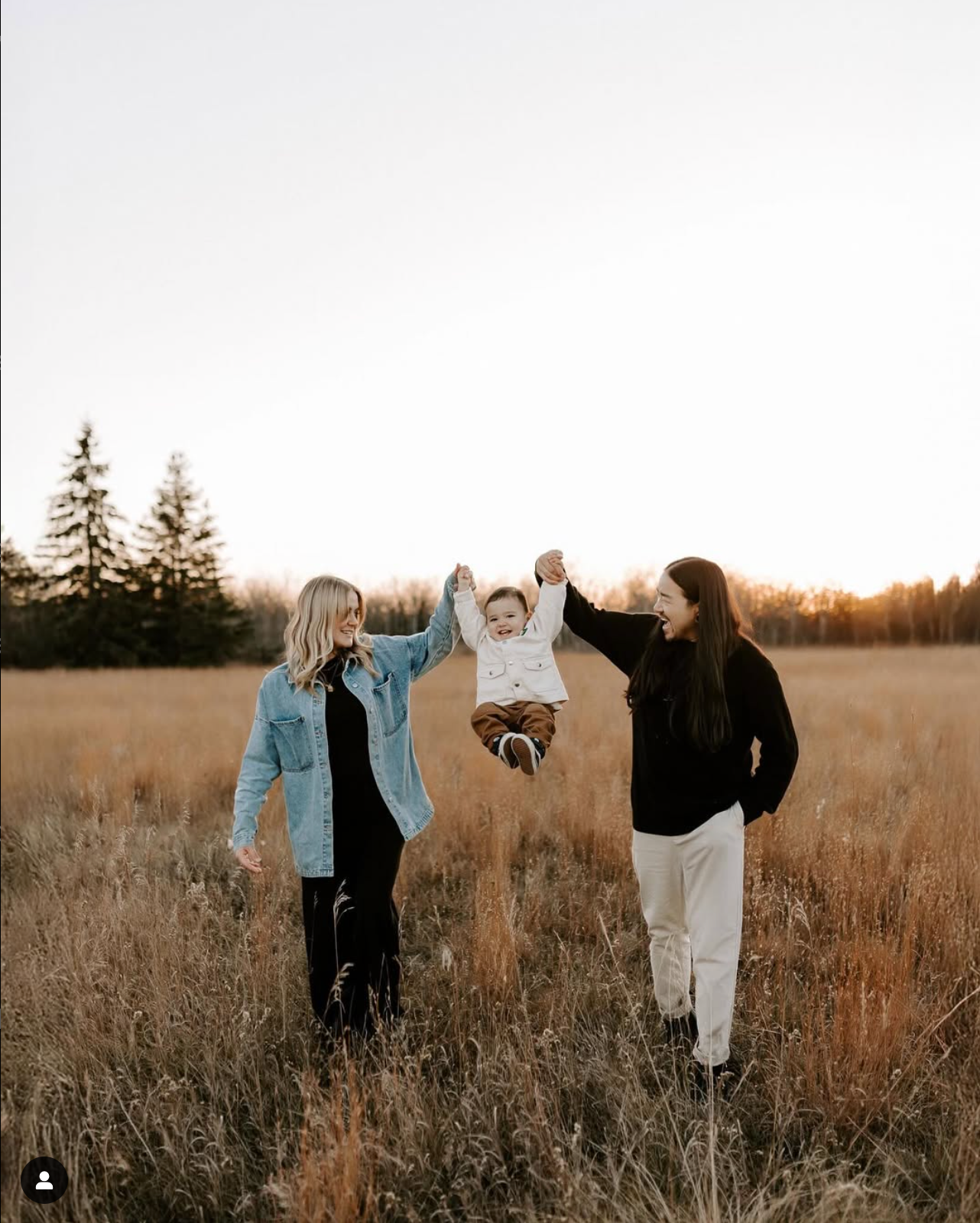 Group playfully dancing and jumping in a golden field at sunset.