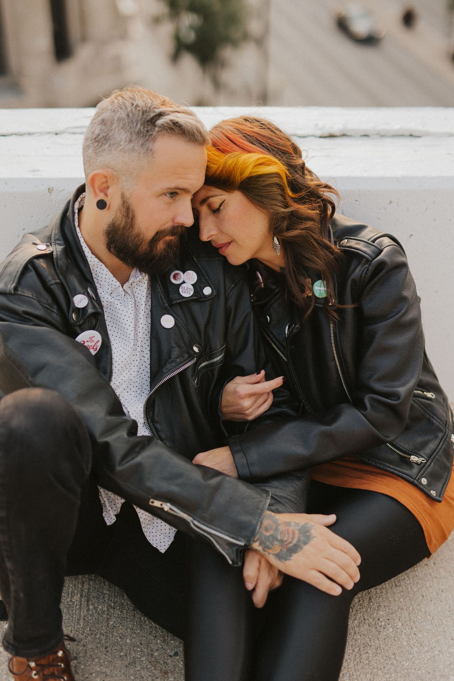 Couple in leather jackets sharing intimate moments while sitting on concrete steps.