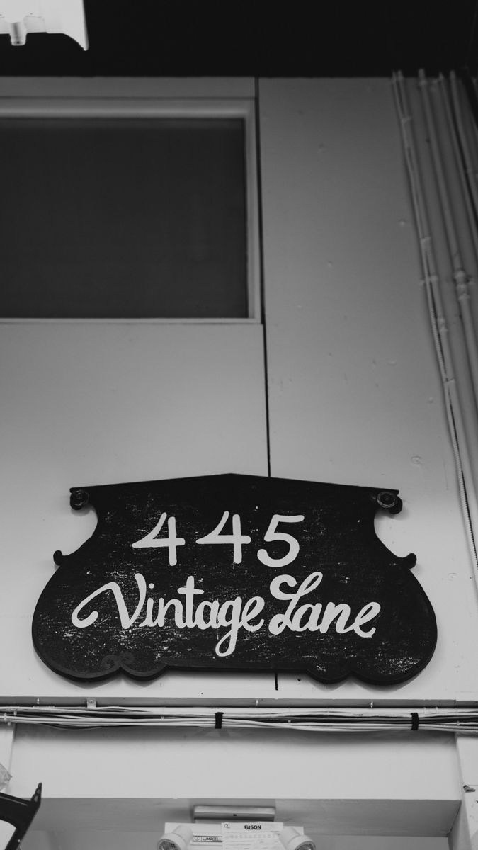 Black vintage-style signage displaying numbers and text mounted on a white wall.