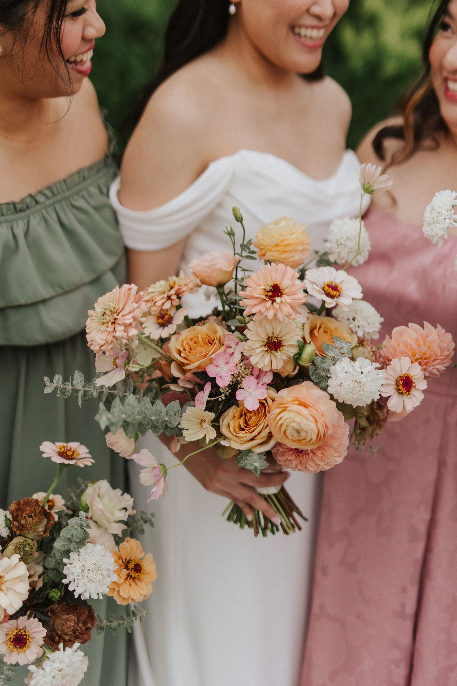 Wedding bouquets in peach, pink and cream colors arranged in a row with roses and dahlias.