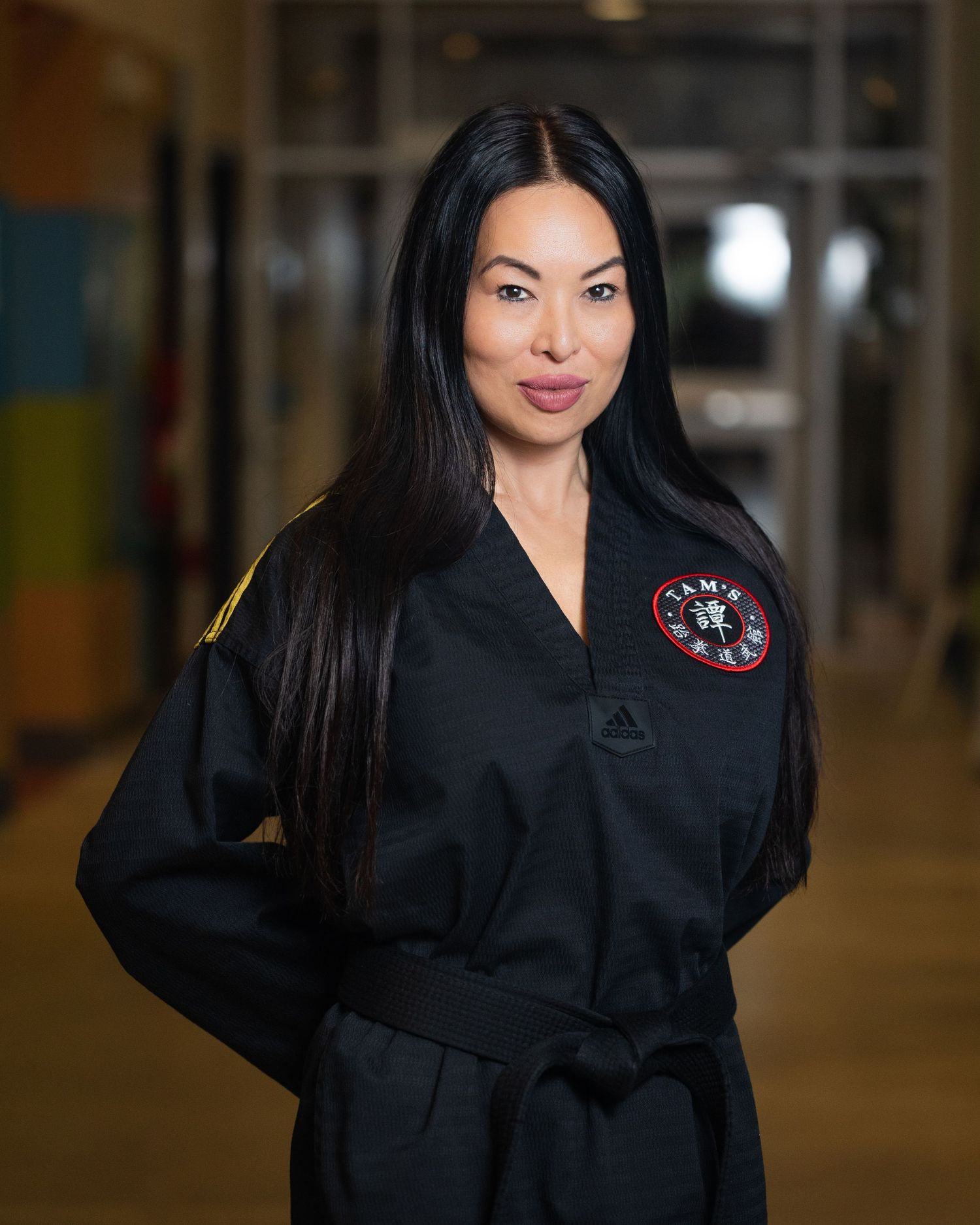 Person wearing black martial arts uniform poses in training facility.