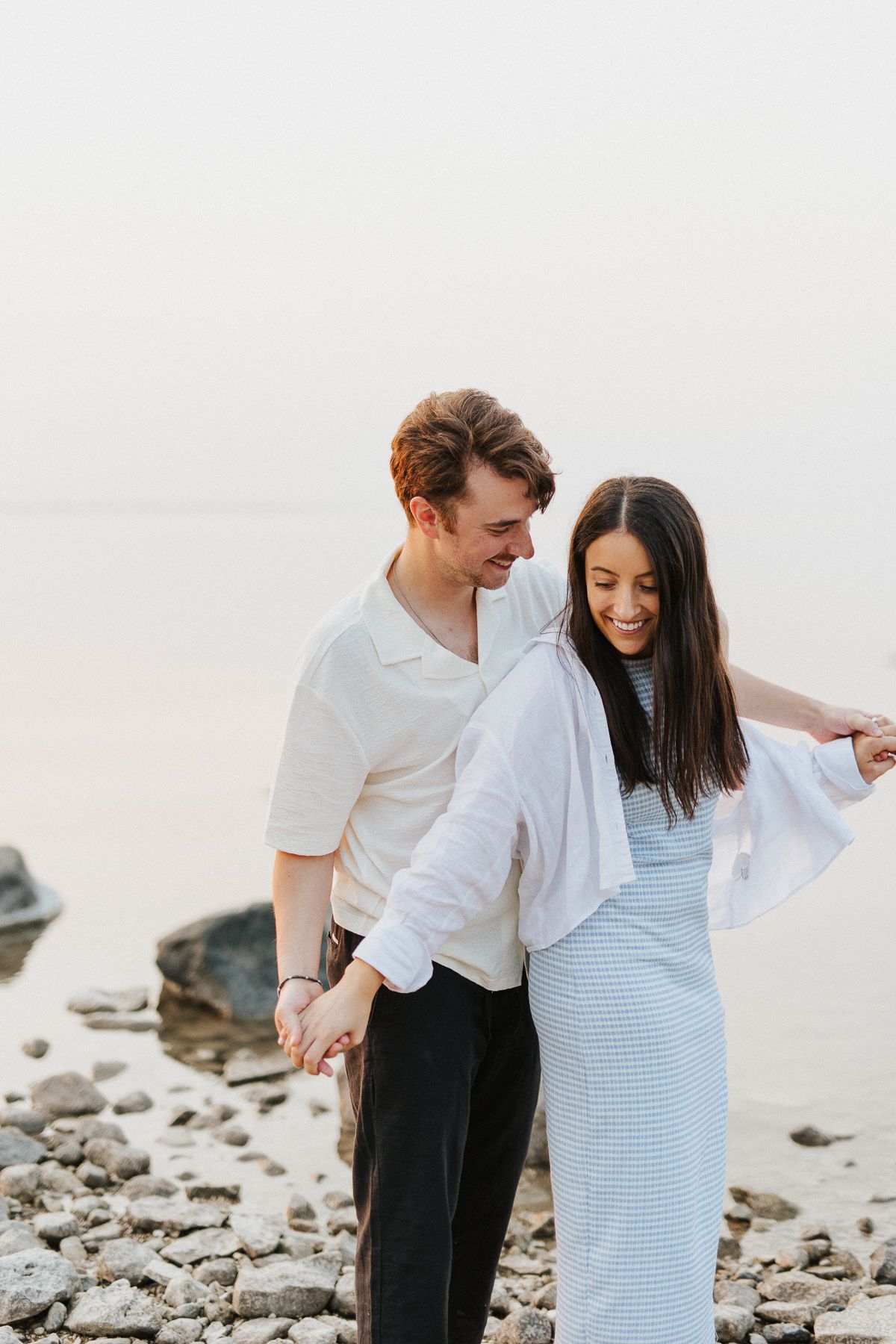 Romantic couple sharing a tender moment on a rocky beach at sunset. Gimli, Manitoba, Canada