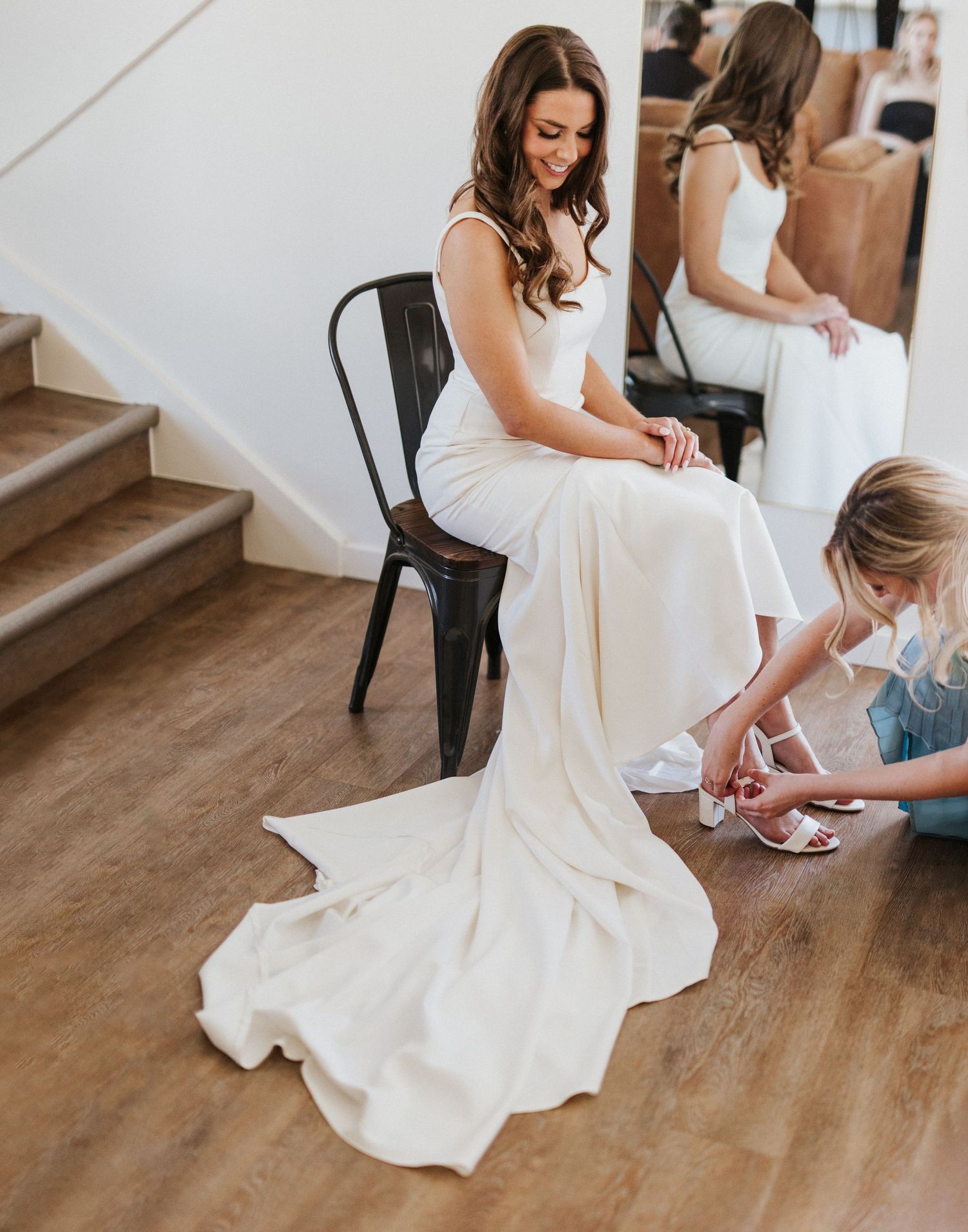 A wedding dress being fitted and adjusted on hardwood floors during bridal preparations.