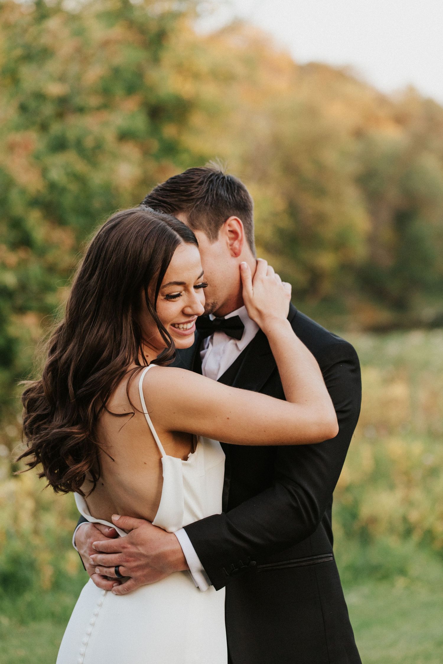 Romantic couple embrace during outdoor wedding photoshoot.