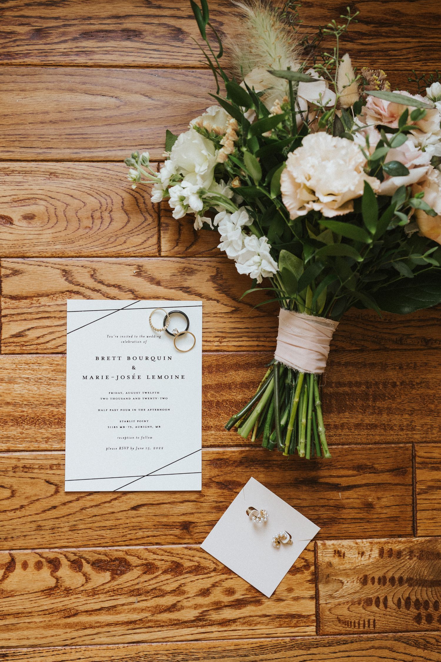 Wedding stationery and floral arrangements displayed on a rustic wooden surface.