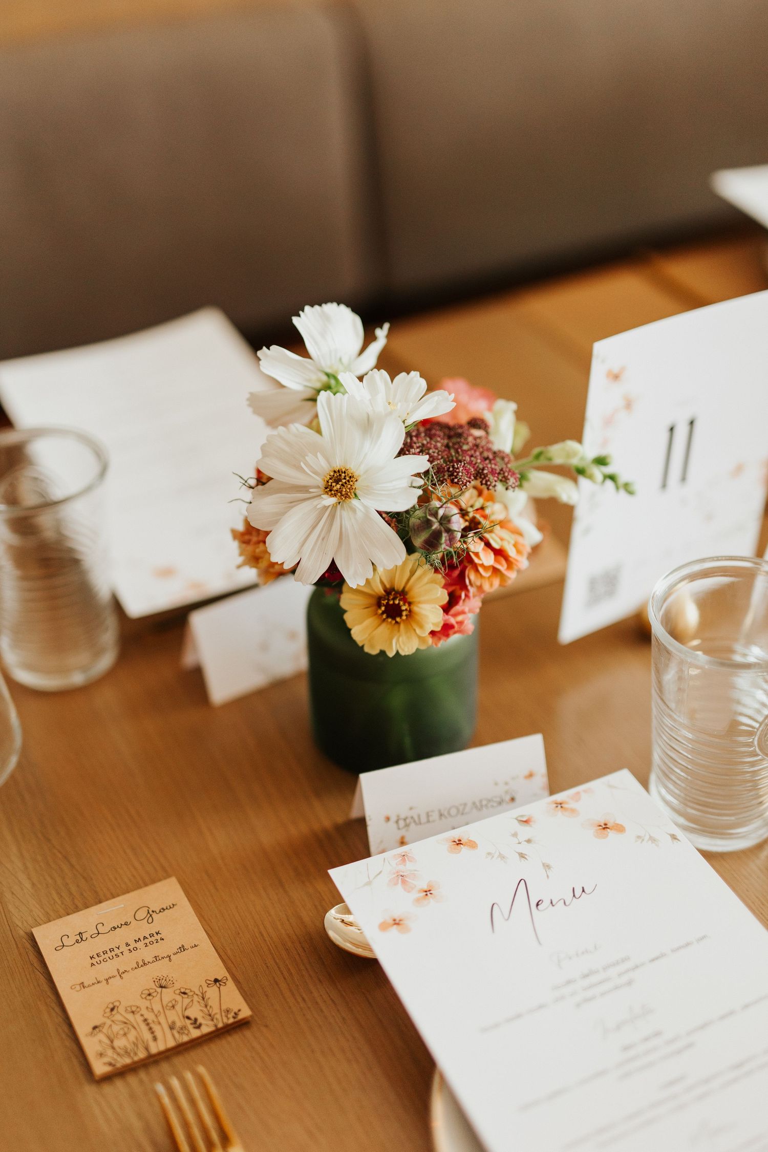 Wedding place cards and menu settings with delicate floral details on wooden table.