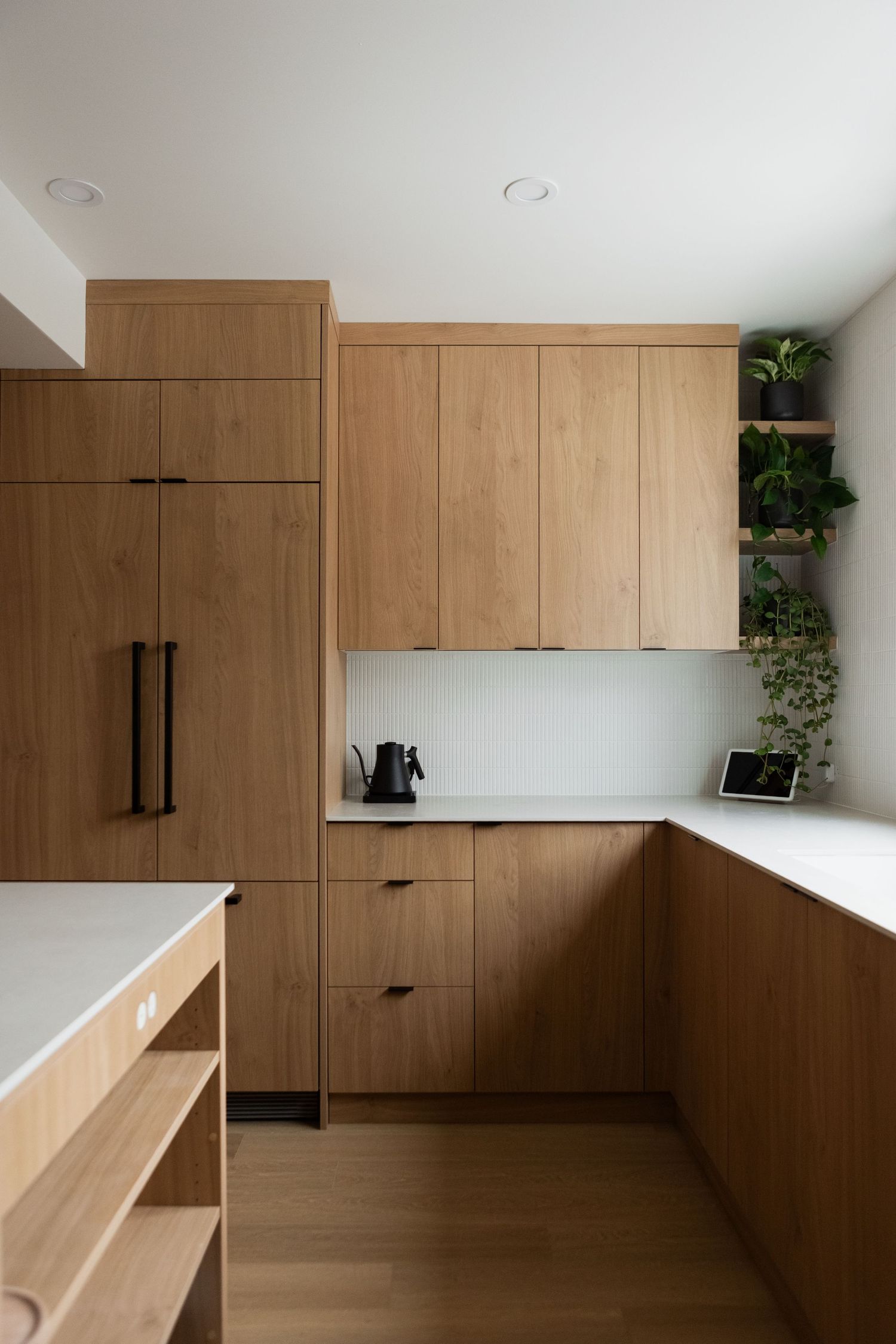 Modern office space with built-in wooden storage and workspace solutions along white walls.
