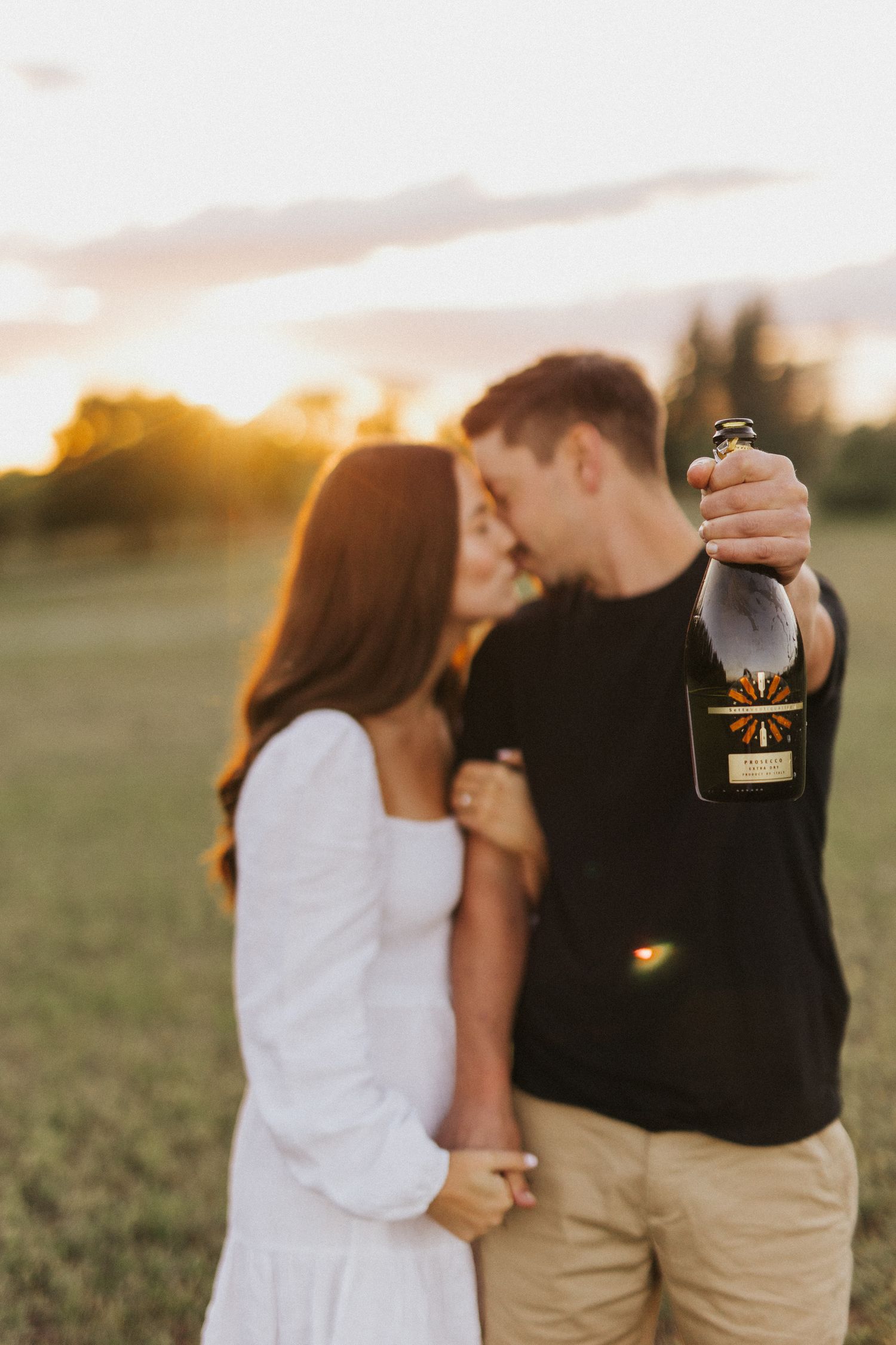 Couple shares intimate moment in countryside during golden hour photography session.