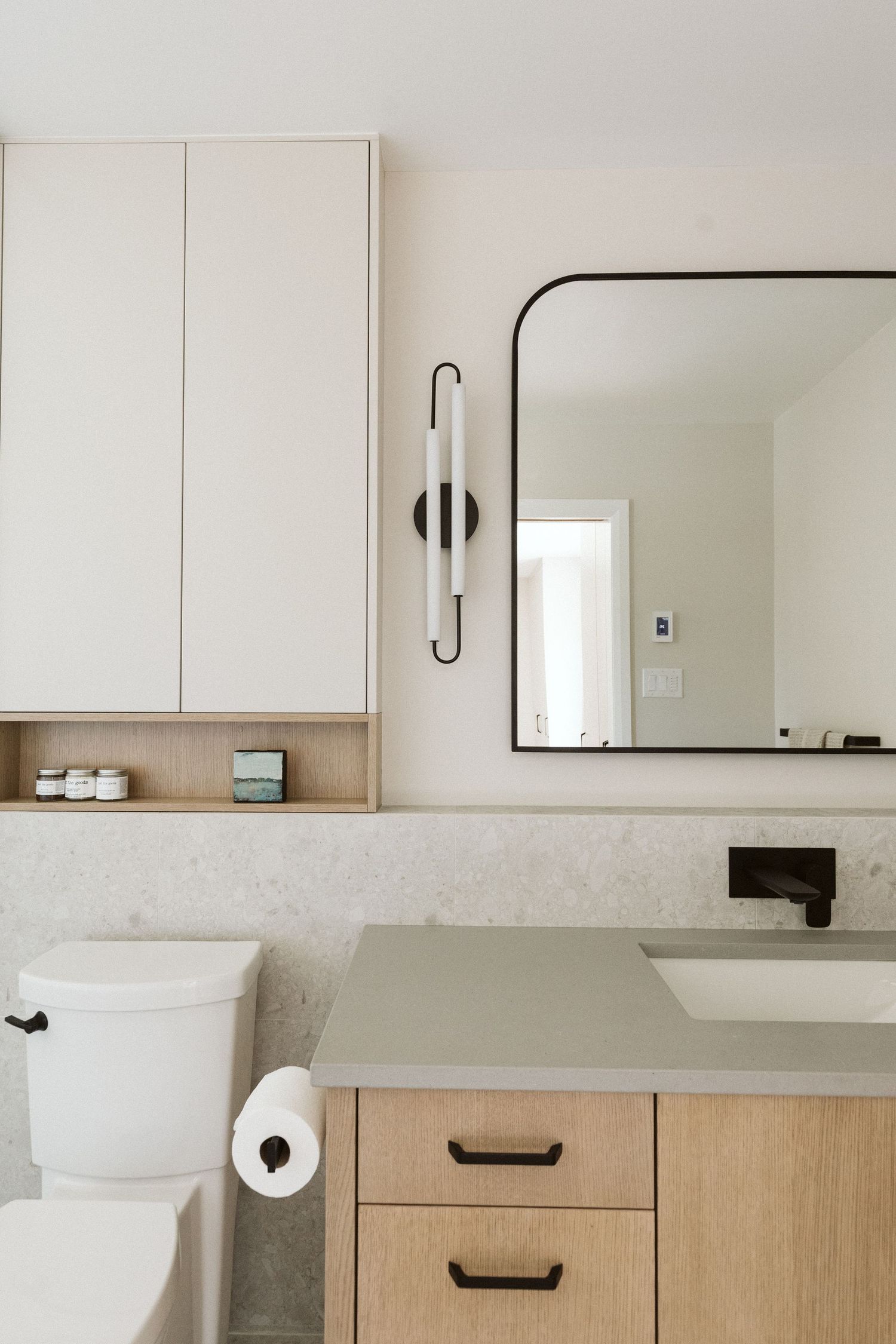 Modern white bathroom interior with wooden vanity cabinets and clean minimalist design.