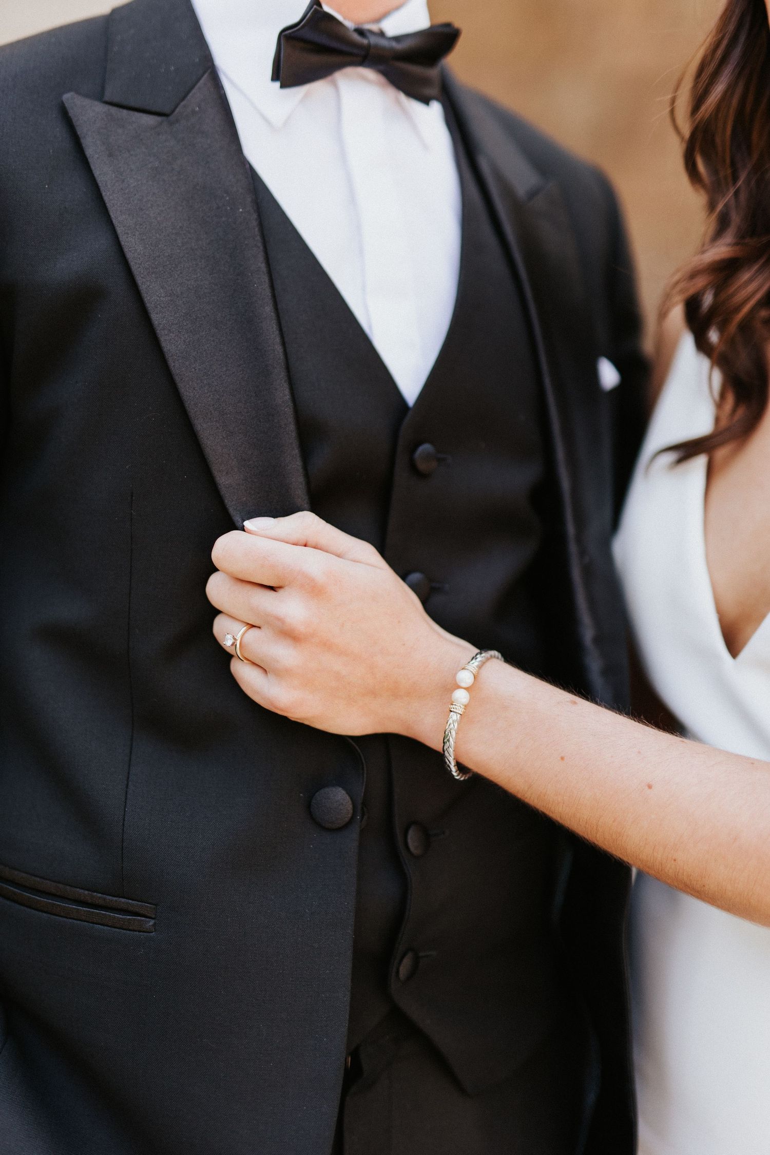 Close-up details of a formal black tuxedo with white dress shirt and bowtie.