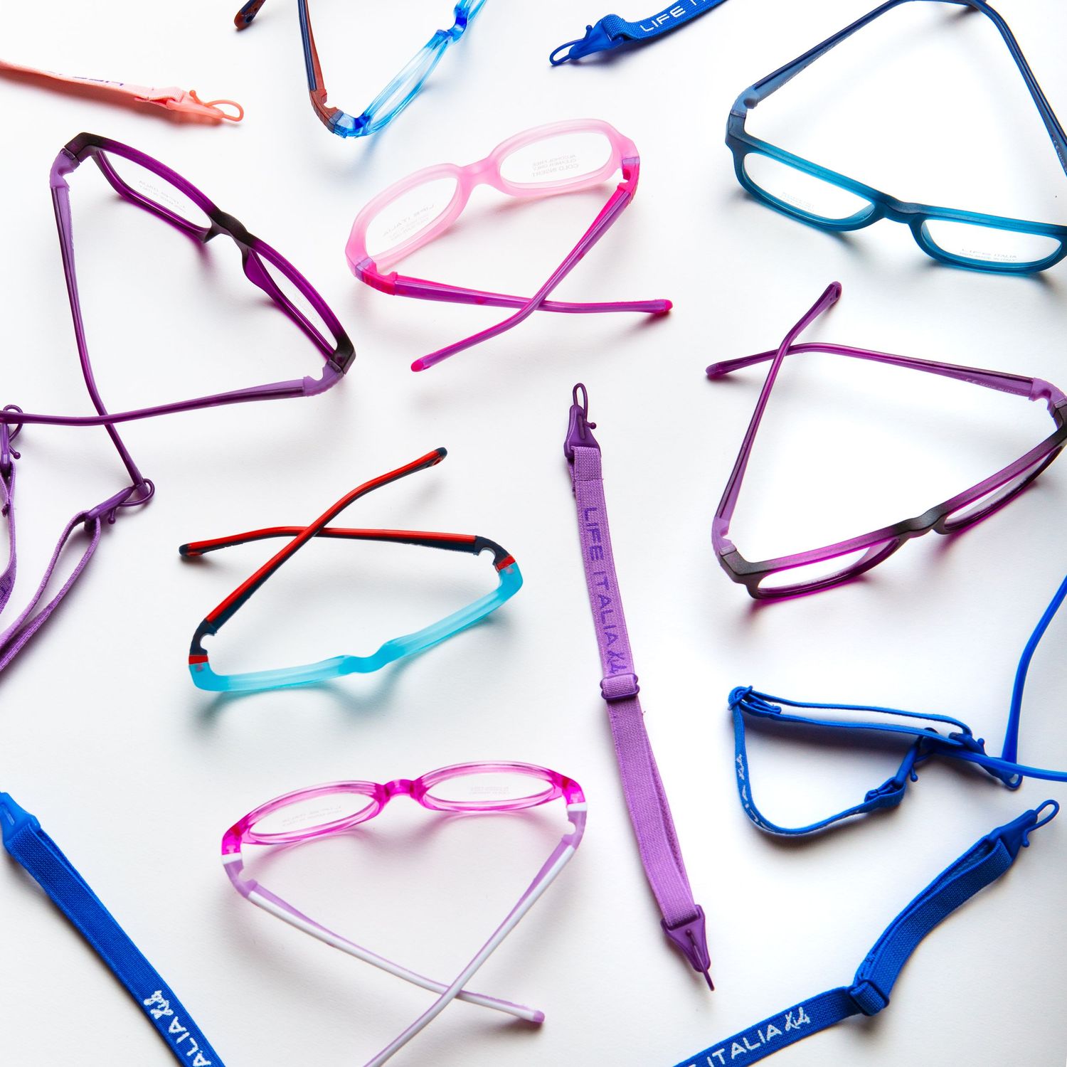 Colorful reading glasses arranged in a scattered pattern on white background.