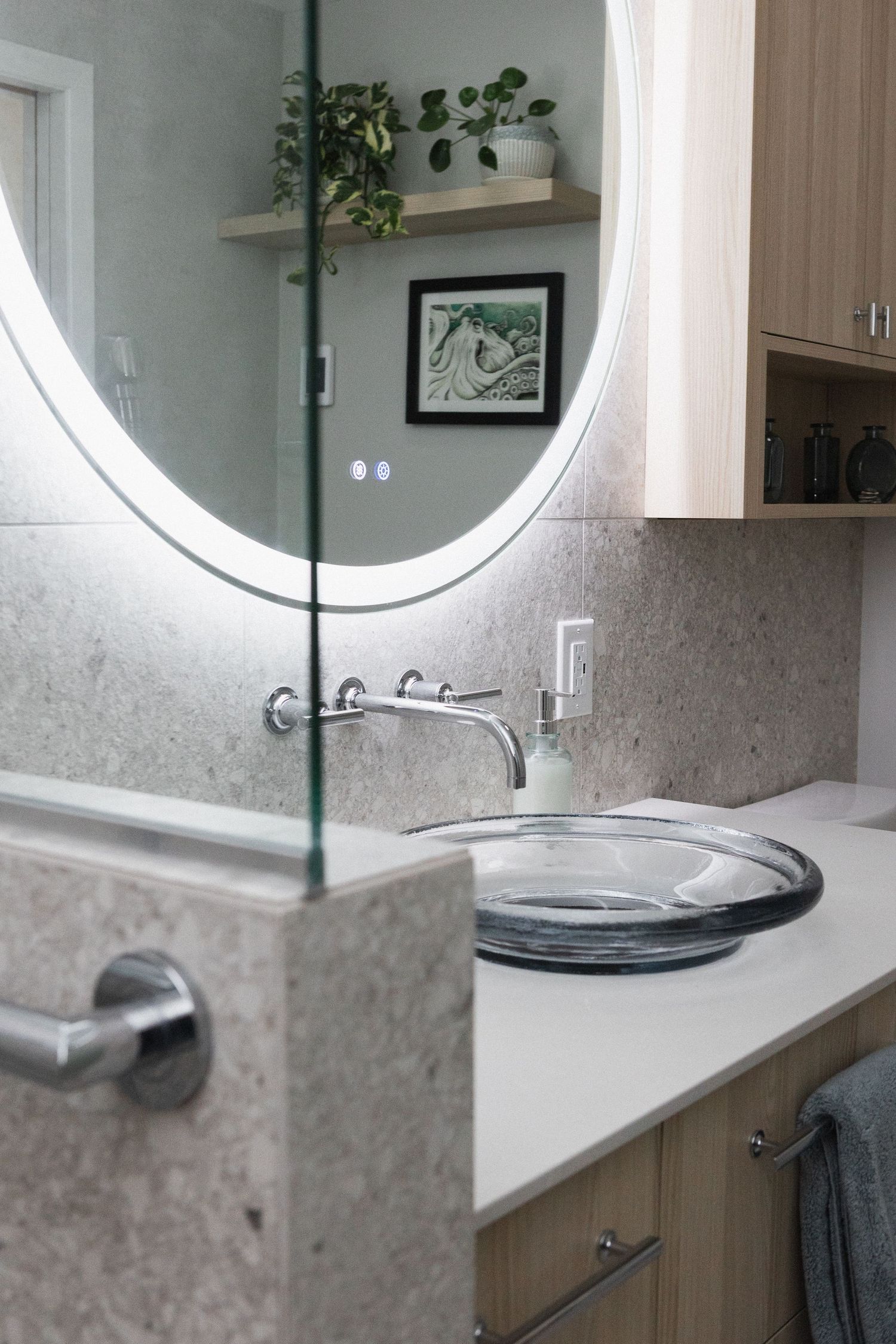 Sleek bathroom vanity with illuminated round mirror and contemporary faucet design.