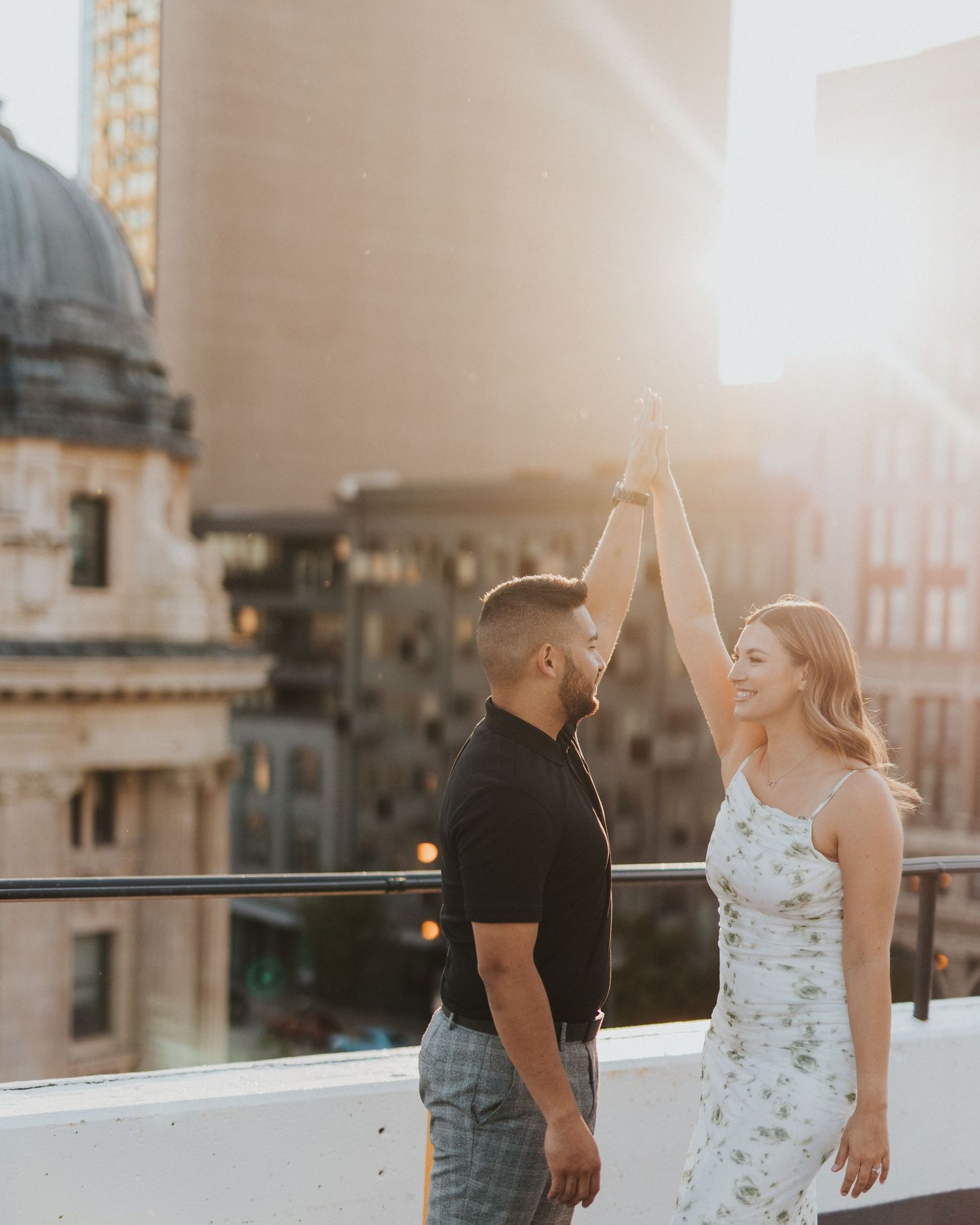 Couple dances together on a rooftop during golden hour in an urban setting.