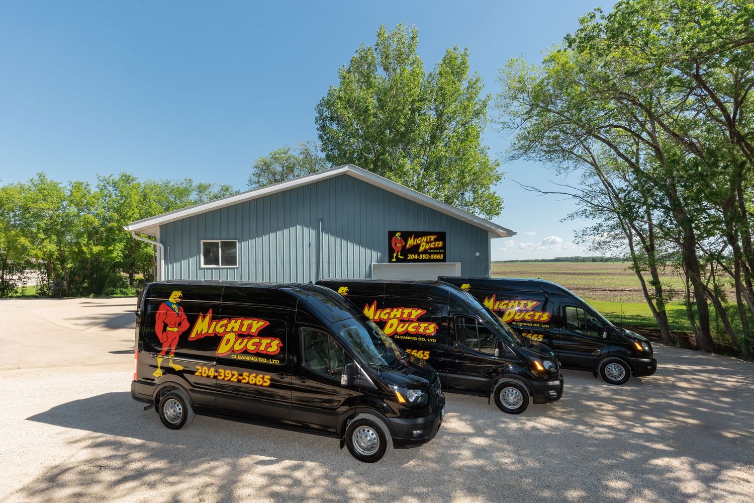 Line of black service vans parked outside business building on sunny day.