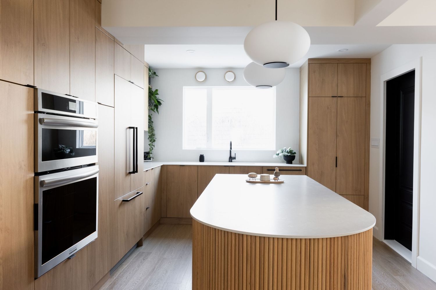 Modern white kitchen featuring clean lines and wood cabinetry with a central island.