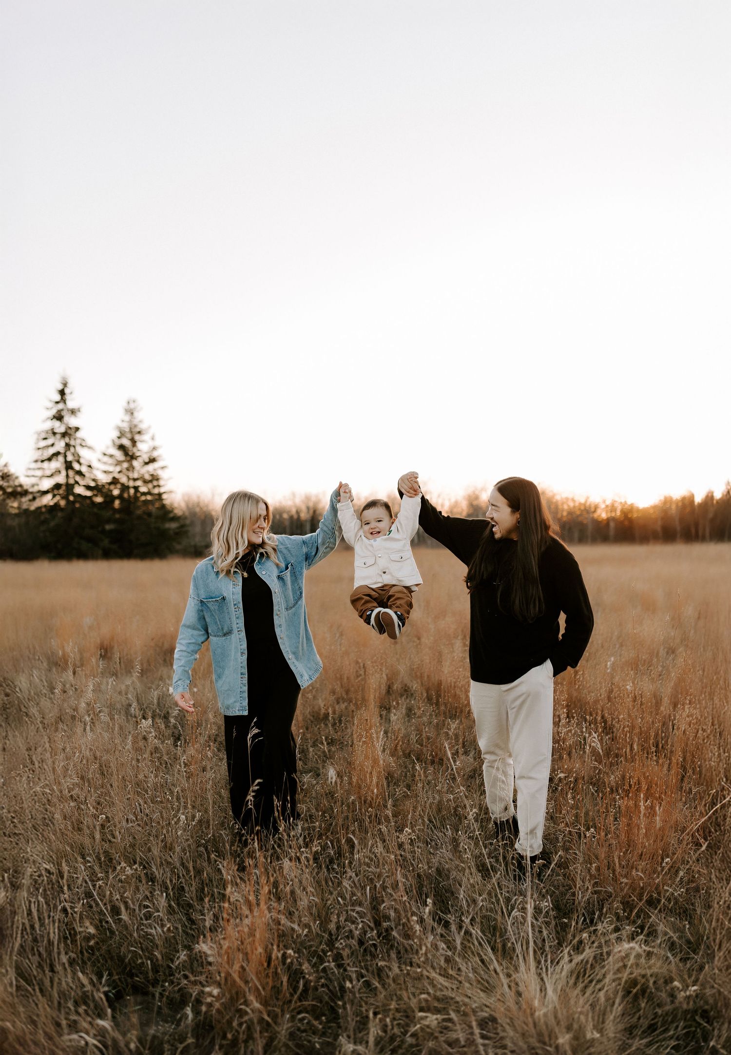 Family having fun in golden field during sunset photoshoot.