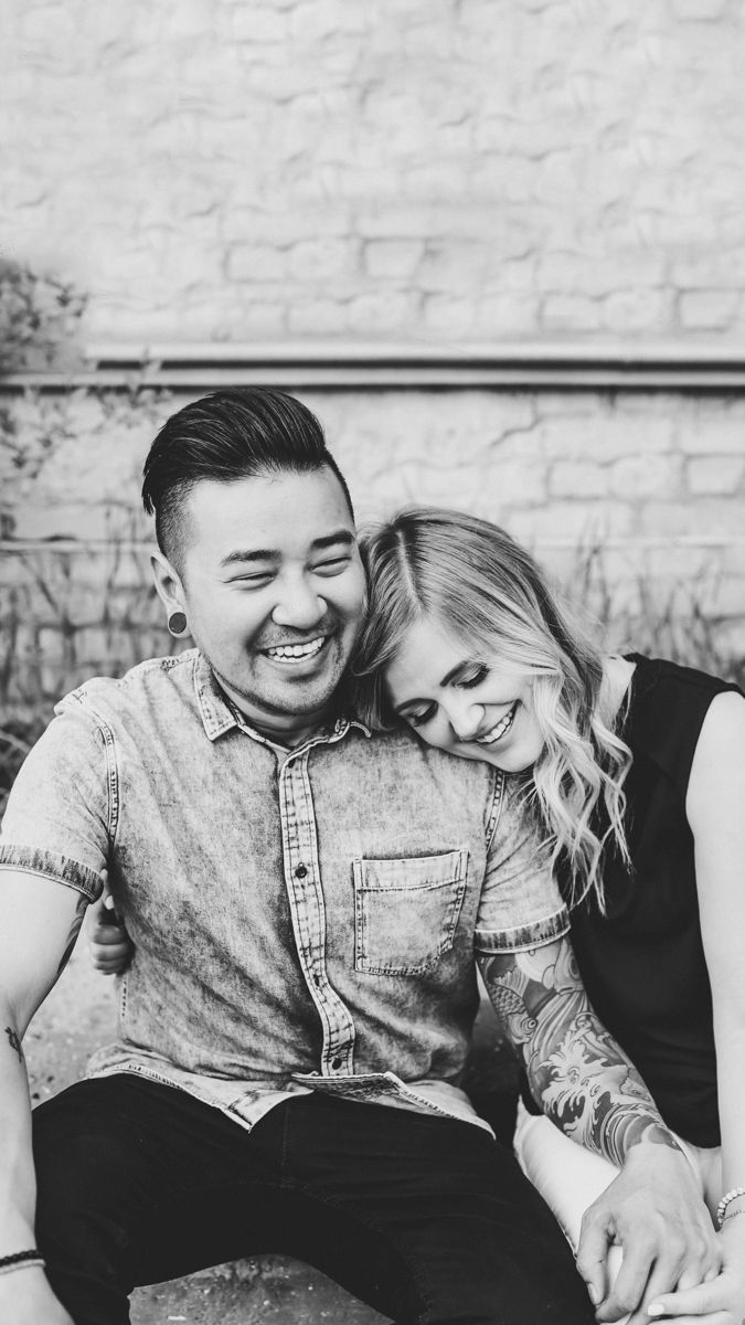Black and white candid photo of a couple laughing together on a couch.