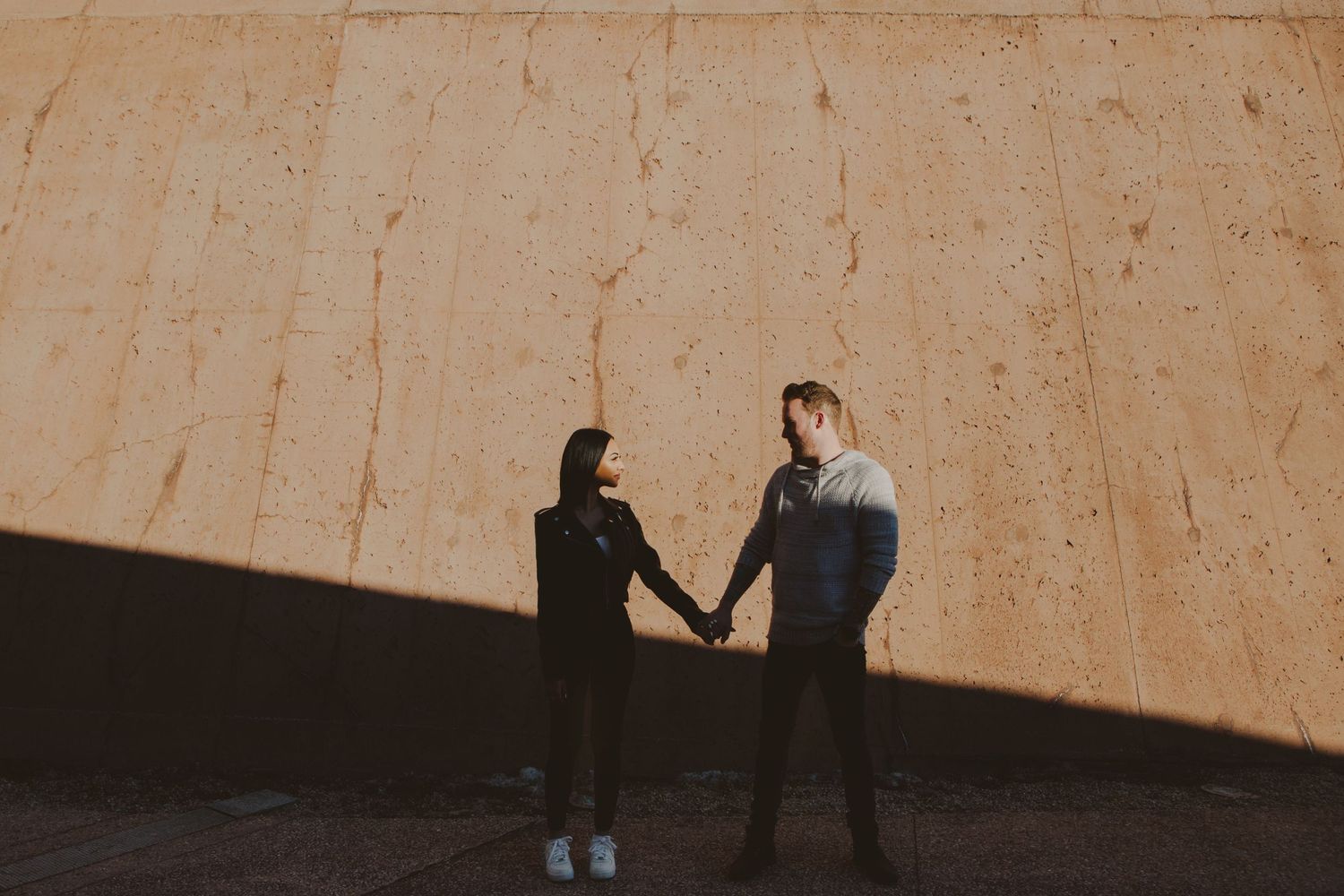 Minimalist sequence showing shadow play of couple against warm sunlit wall.