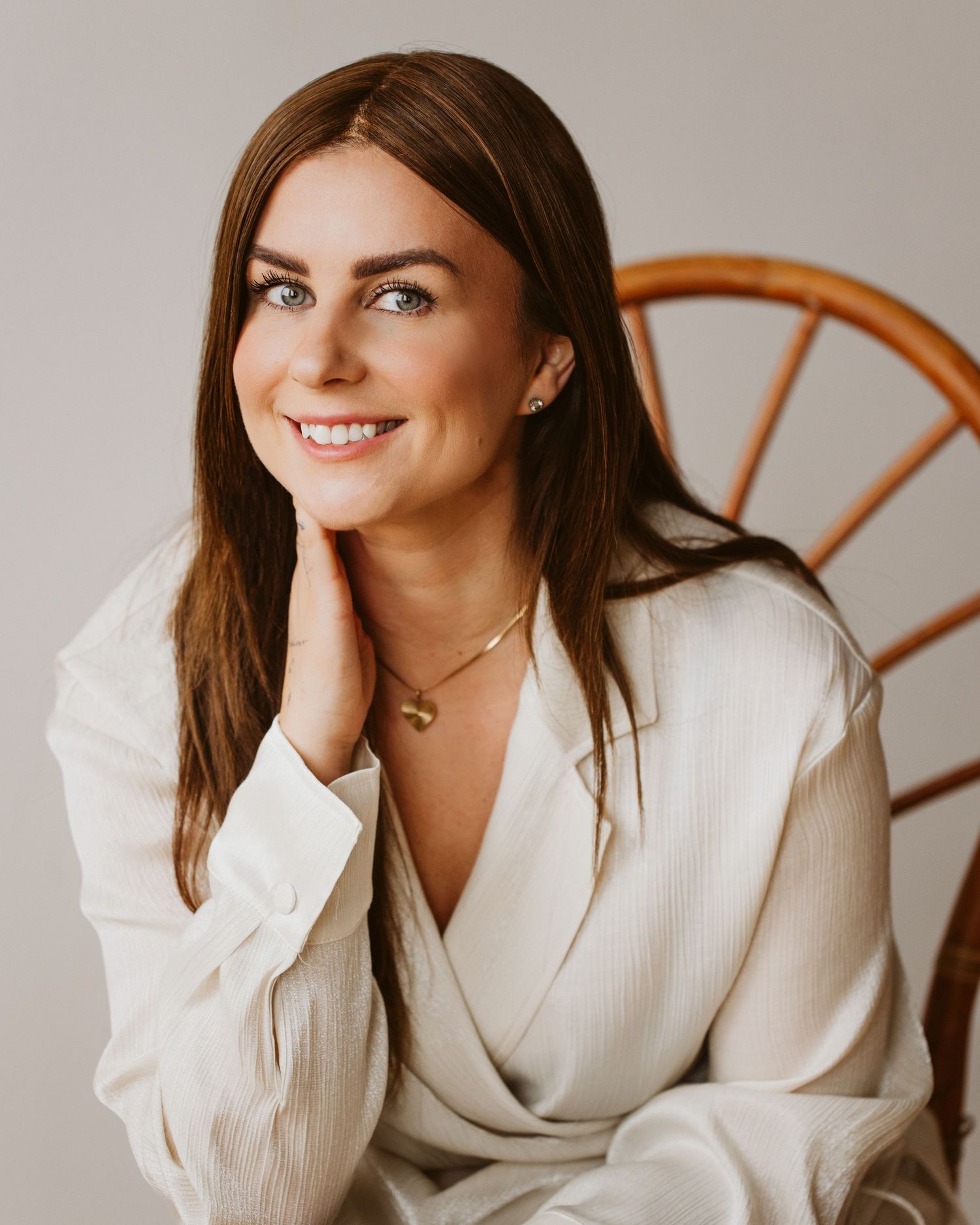 Professional headshots in white blazer against neutral backdrop.