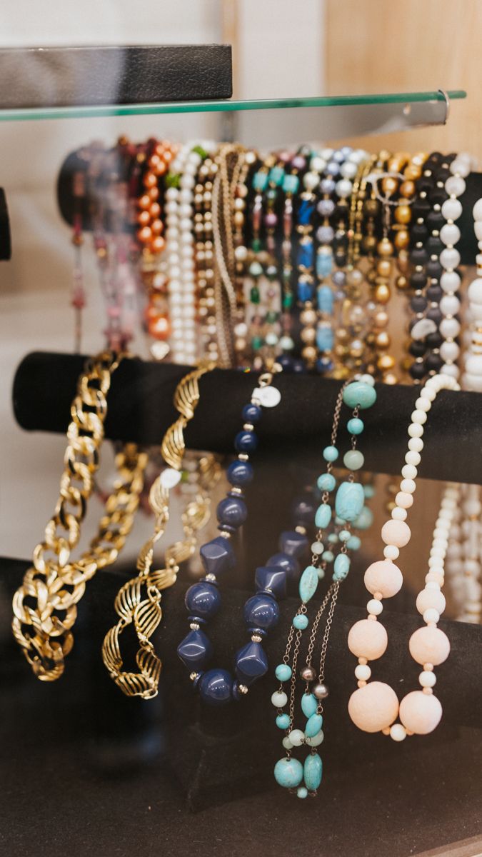 Colorful beaded necklaces and jewelry displayed on black hanging racks.