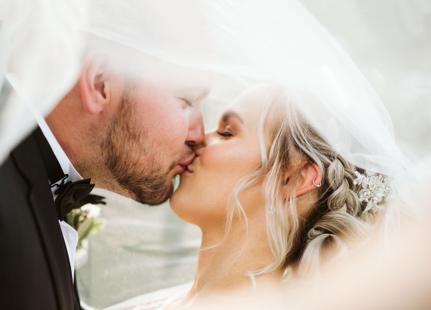 Soft, romantic wedding portrait with flowing white veil in natural light.