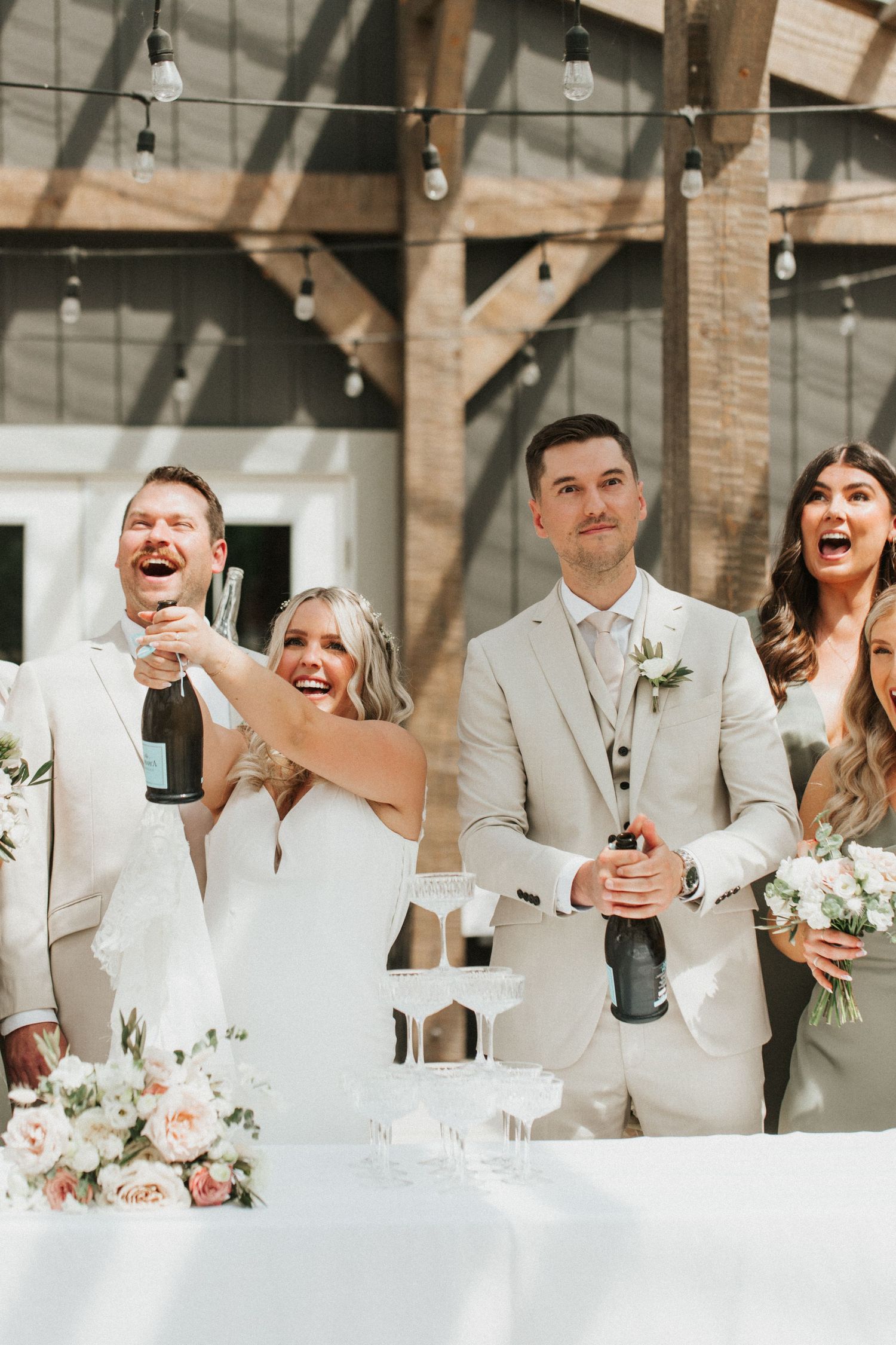 Wedding party laughing and celebrating during reception in rustic venue.