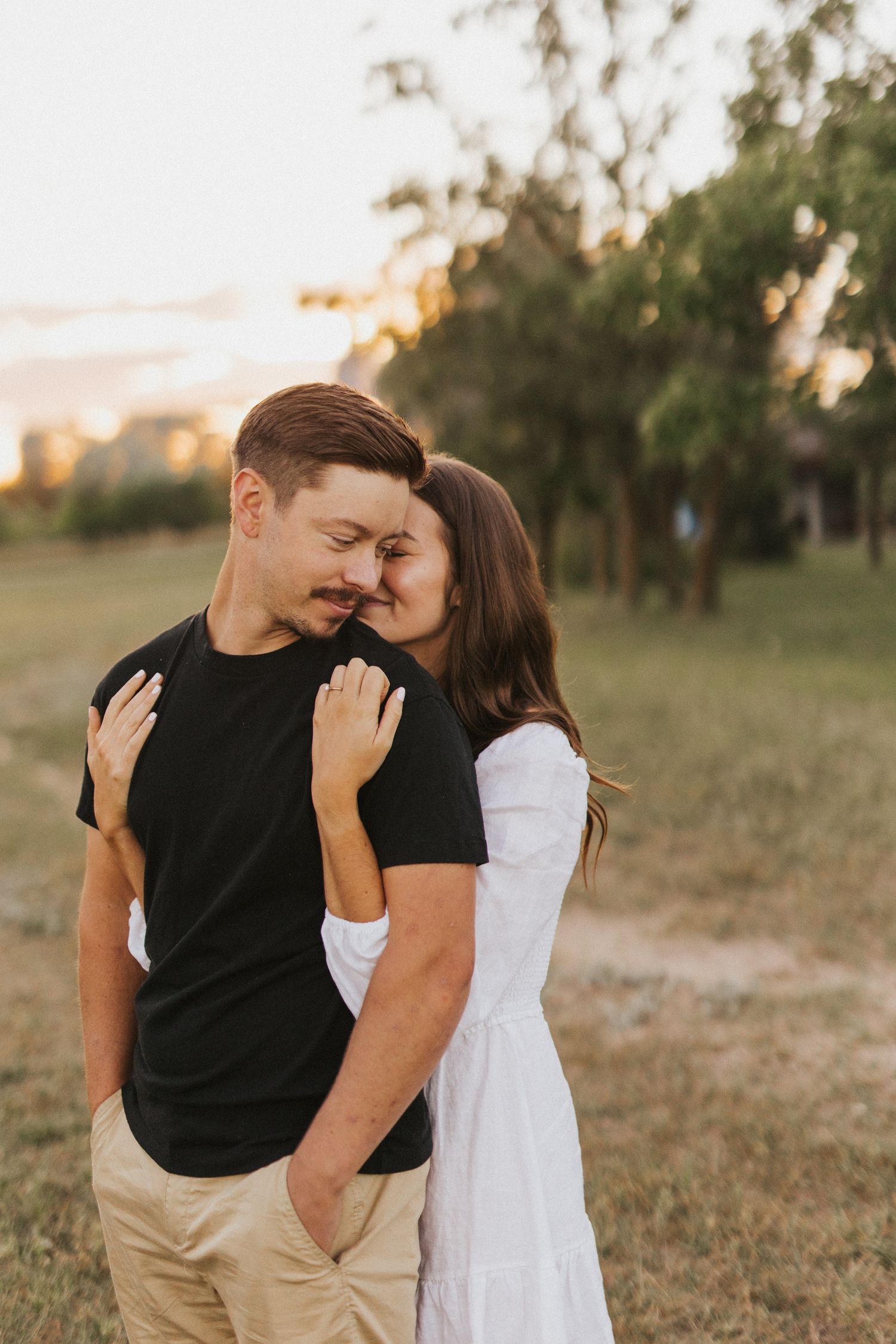Candid moments captured between couple in outdoor field setting.