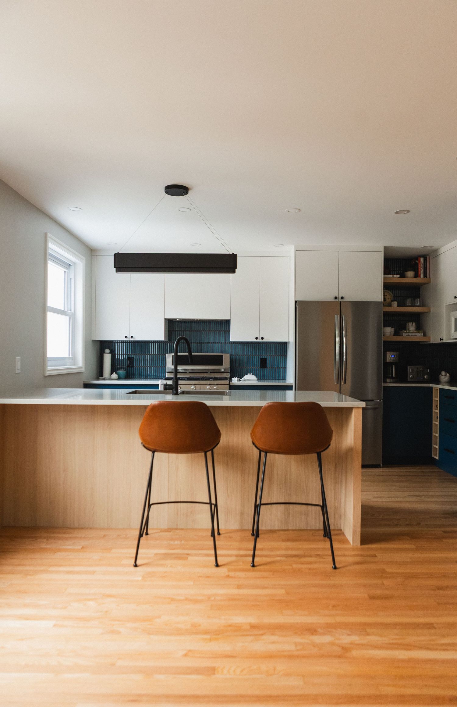 Contemporary kitchen island with brown leather bar stools and hardwood flooring.