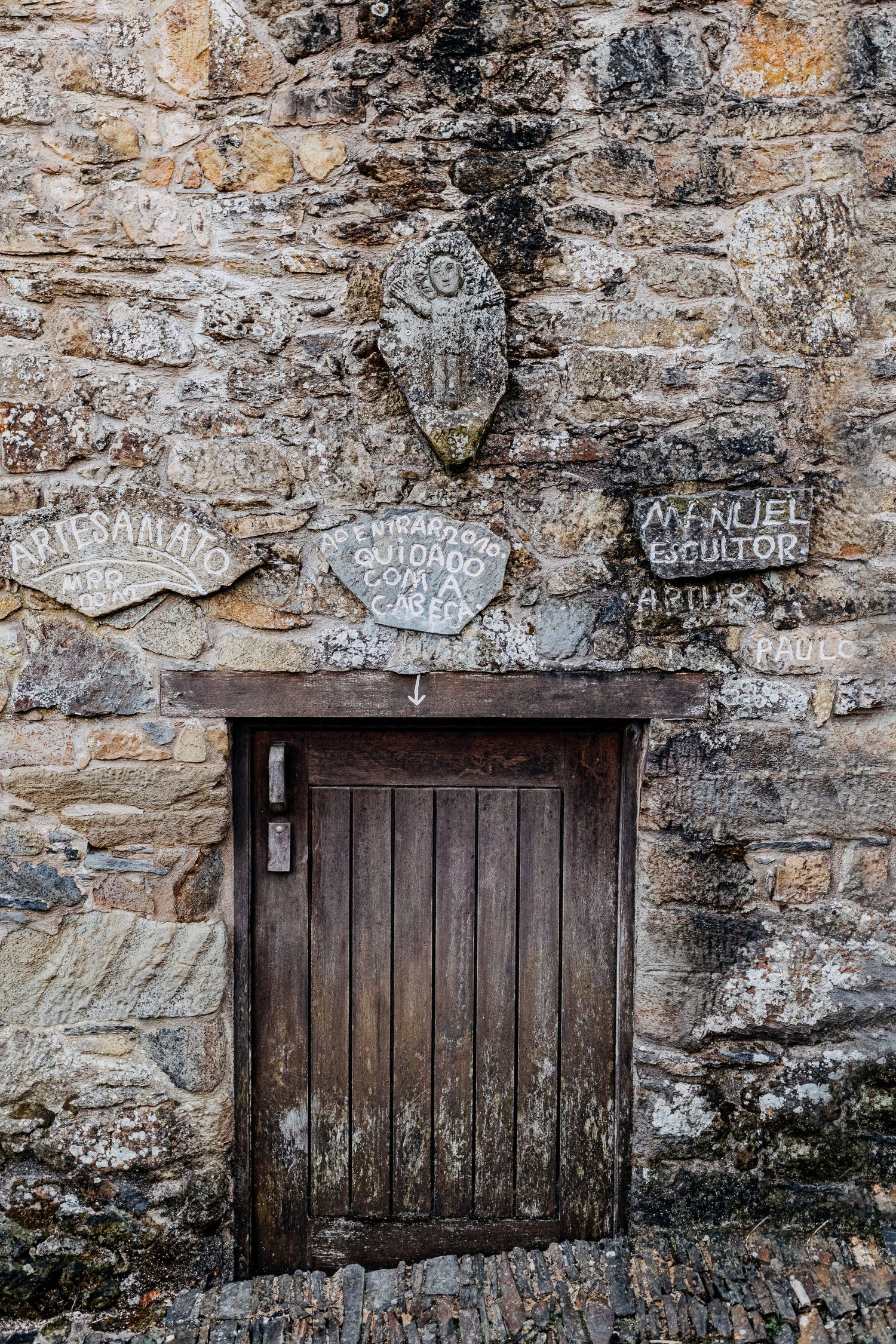Rustic wooden cellar doors set into an old stone wall with faded graffiti markings above them.