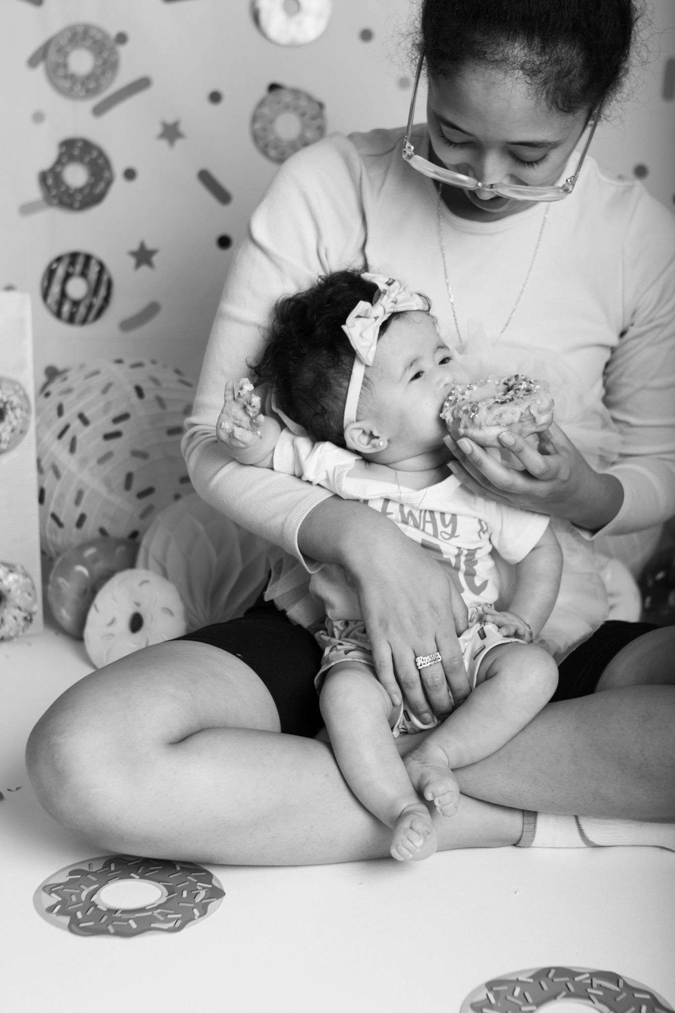 Black and white photo of parent feeding baby in donut-themed room.