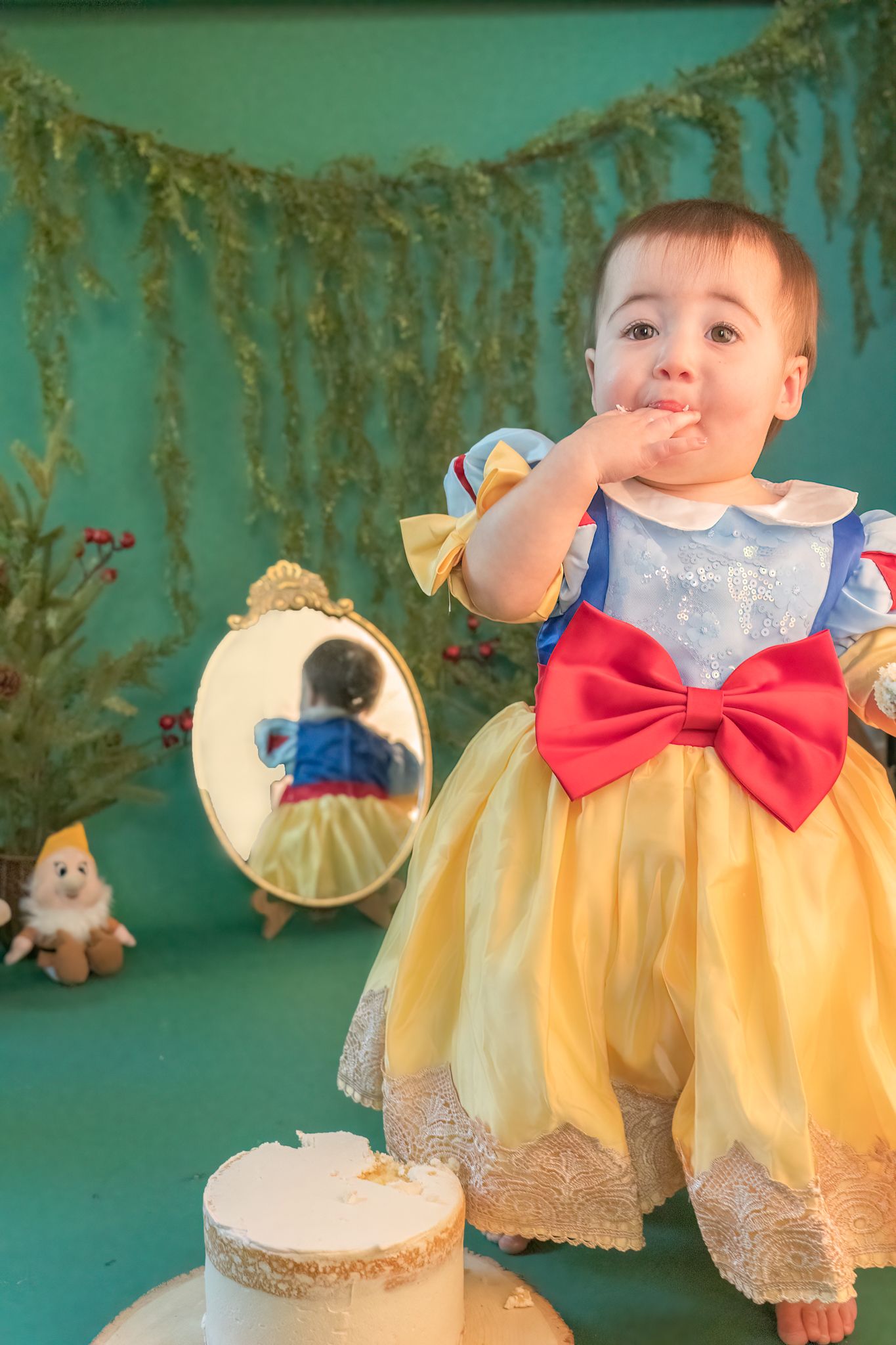 Princess themed cake smash photoshoot with gold garland and ornate mirror.