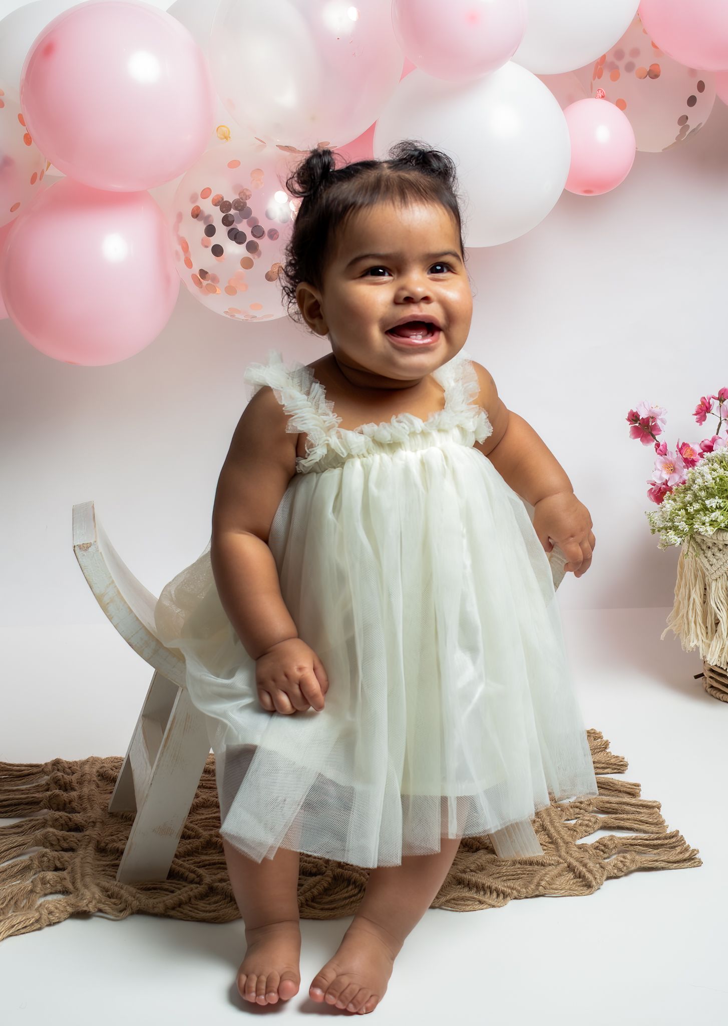 Birthday photo shoot with pink and white balloons and floral decorations.