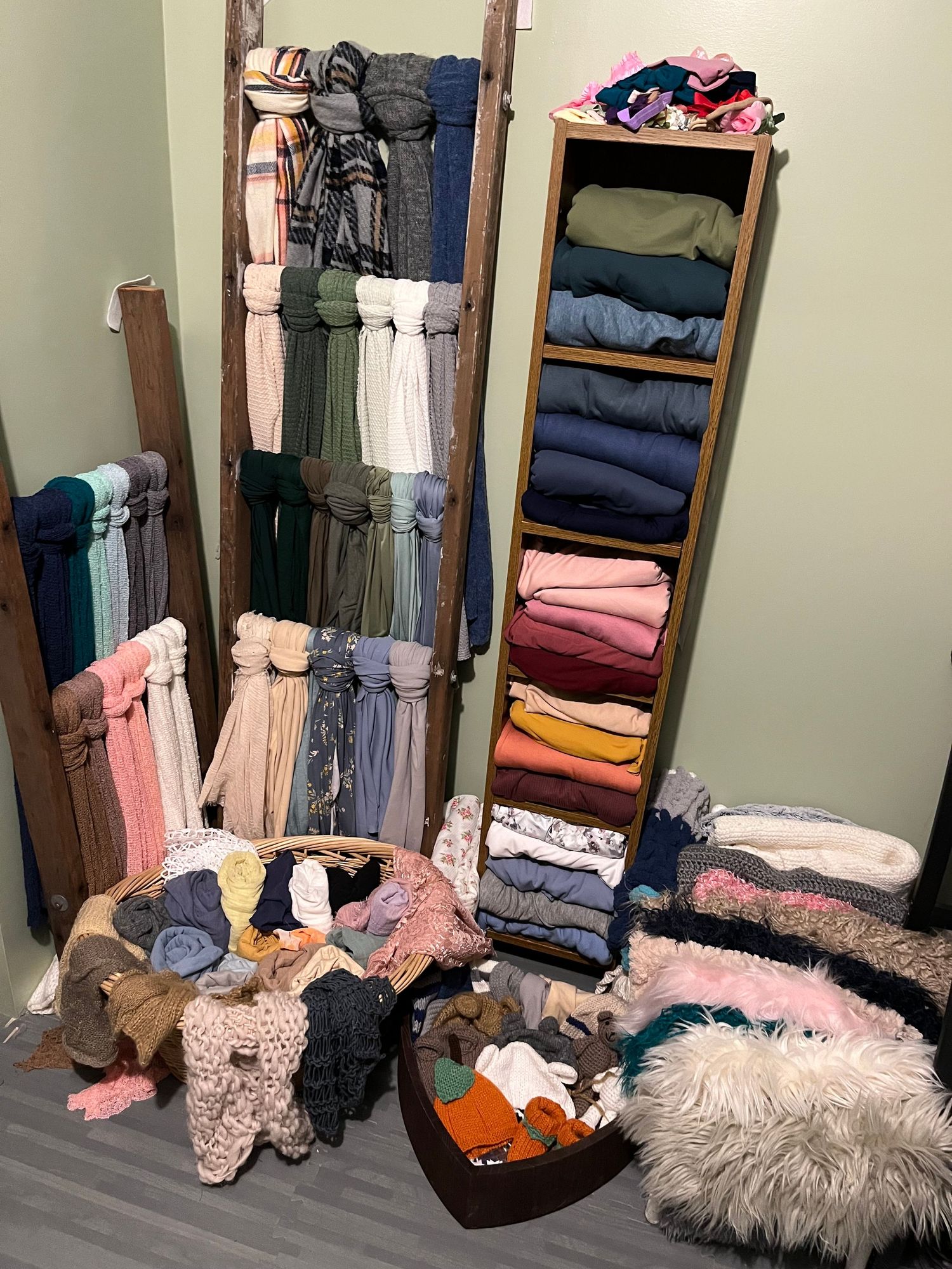 Organized clothing storage with ladder rack and shelving unit displaying folded garments and accessories.