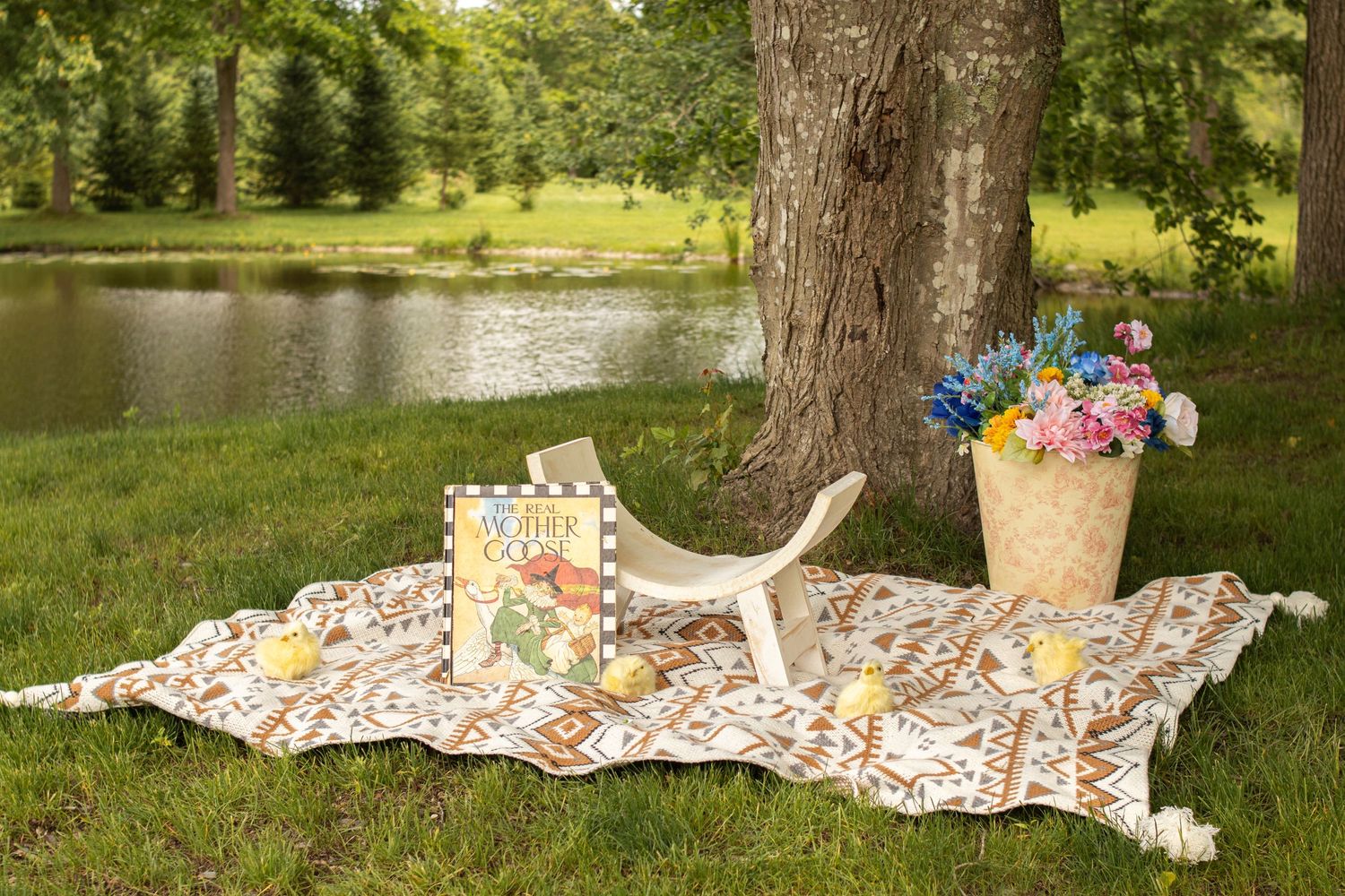 Picnic blanket laid out under a tree by a pond with flowers in Massachusetts