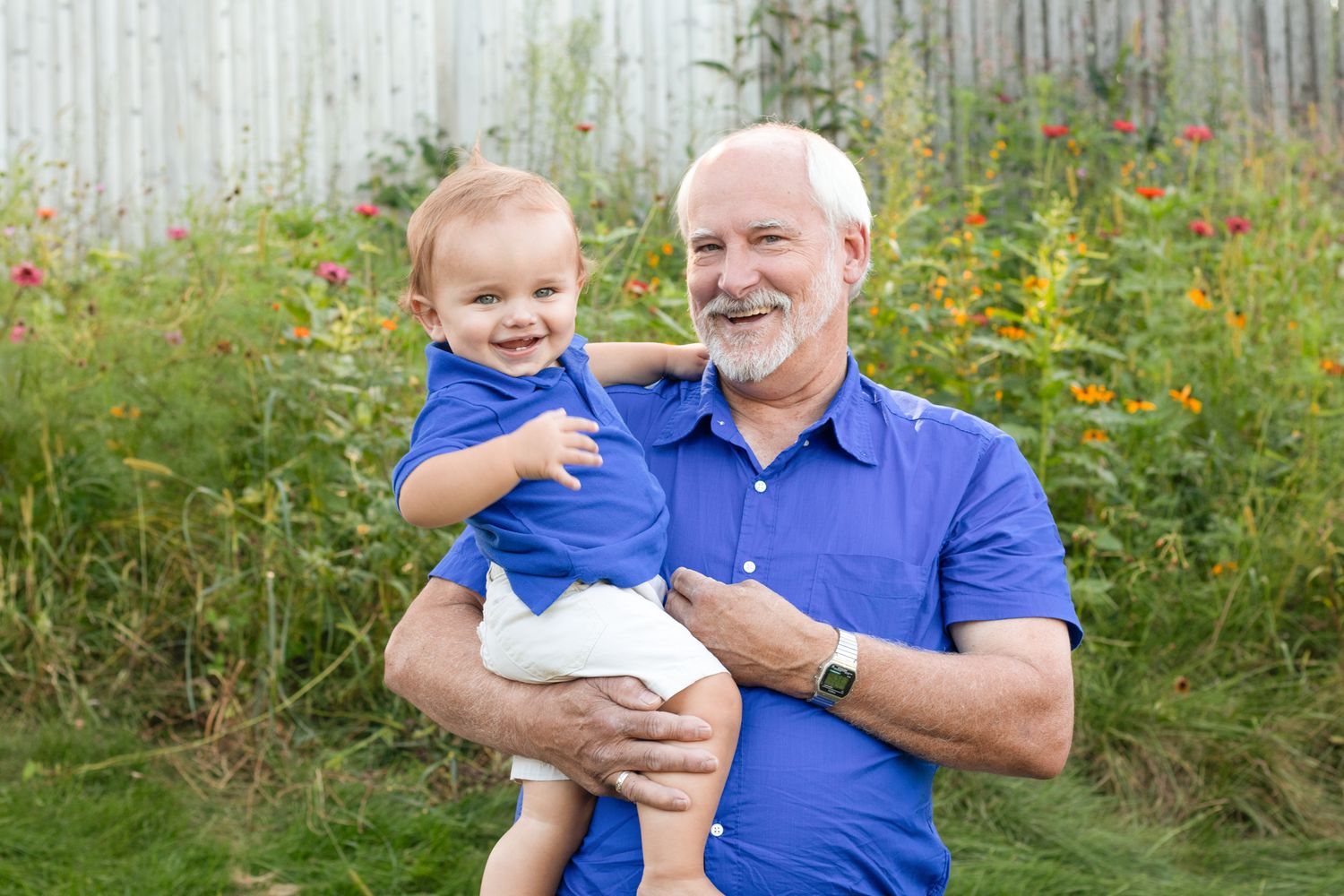 Outdoor portrait in garden with flowers and wooden fence background.