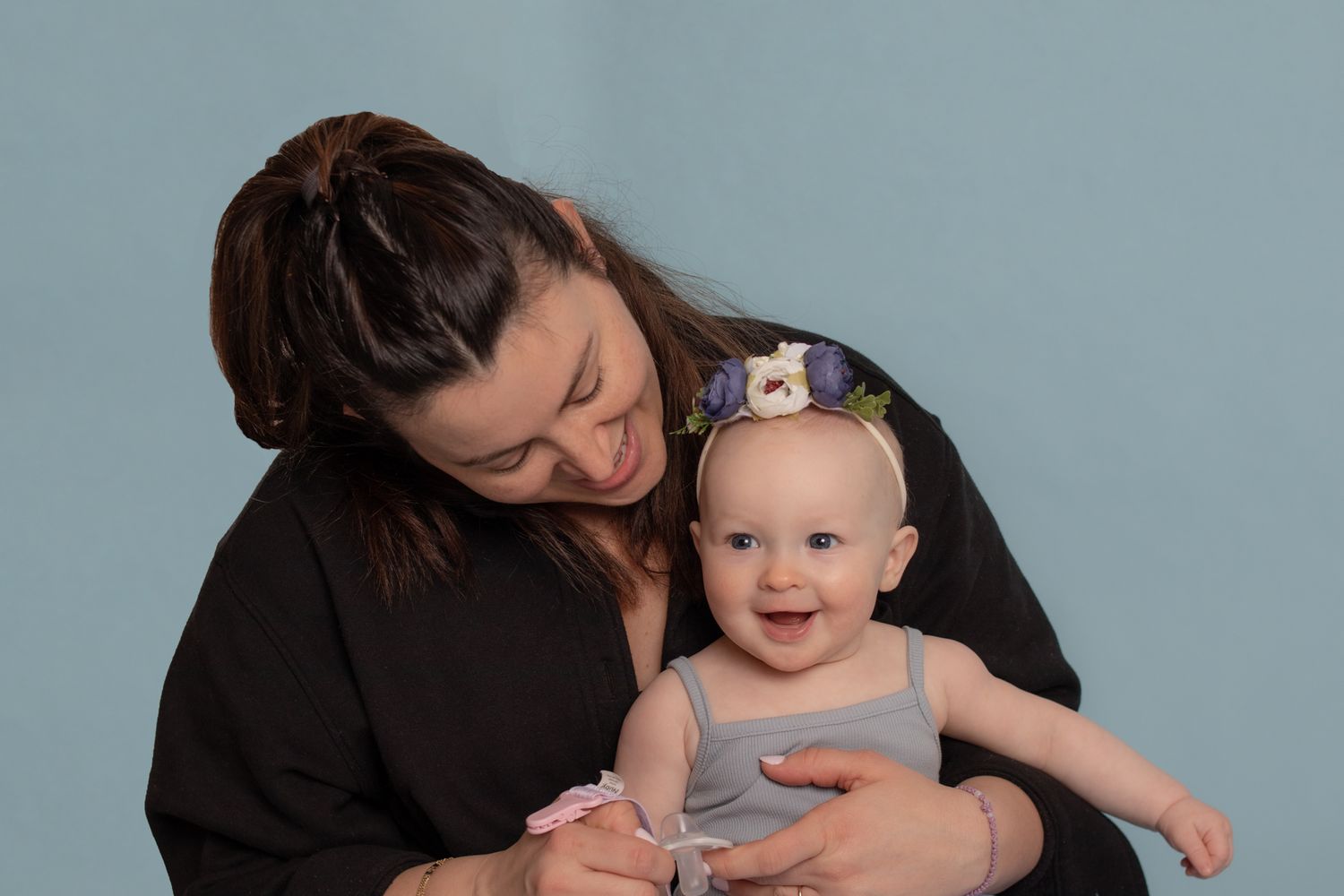 A tender moment between mother and baby against a light blue backdrop.