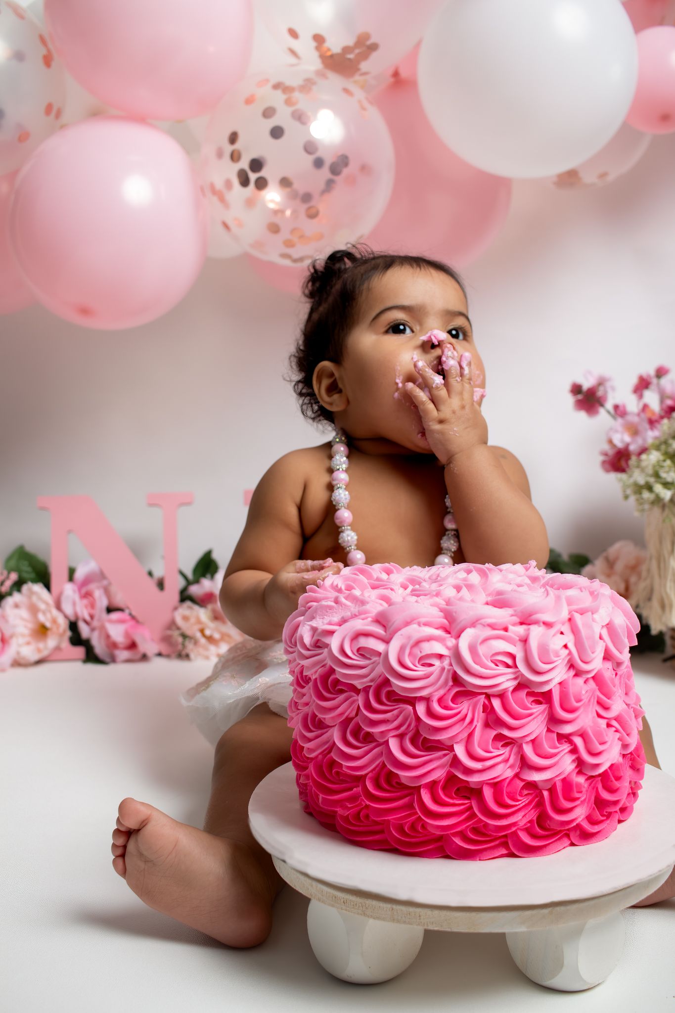 First birthday celebration with pink ombre rosette cake and pink balloon decorations.