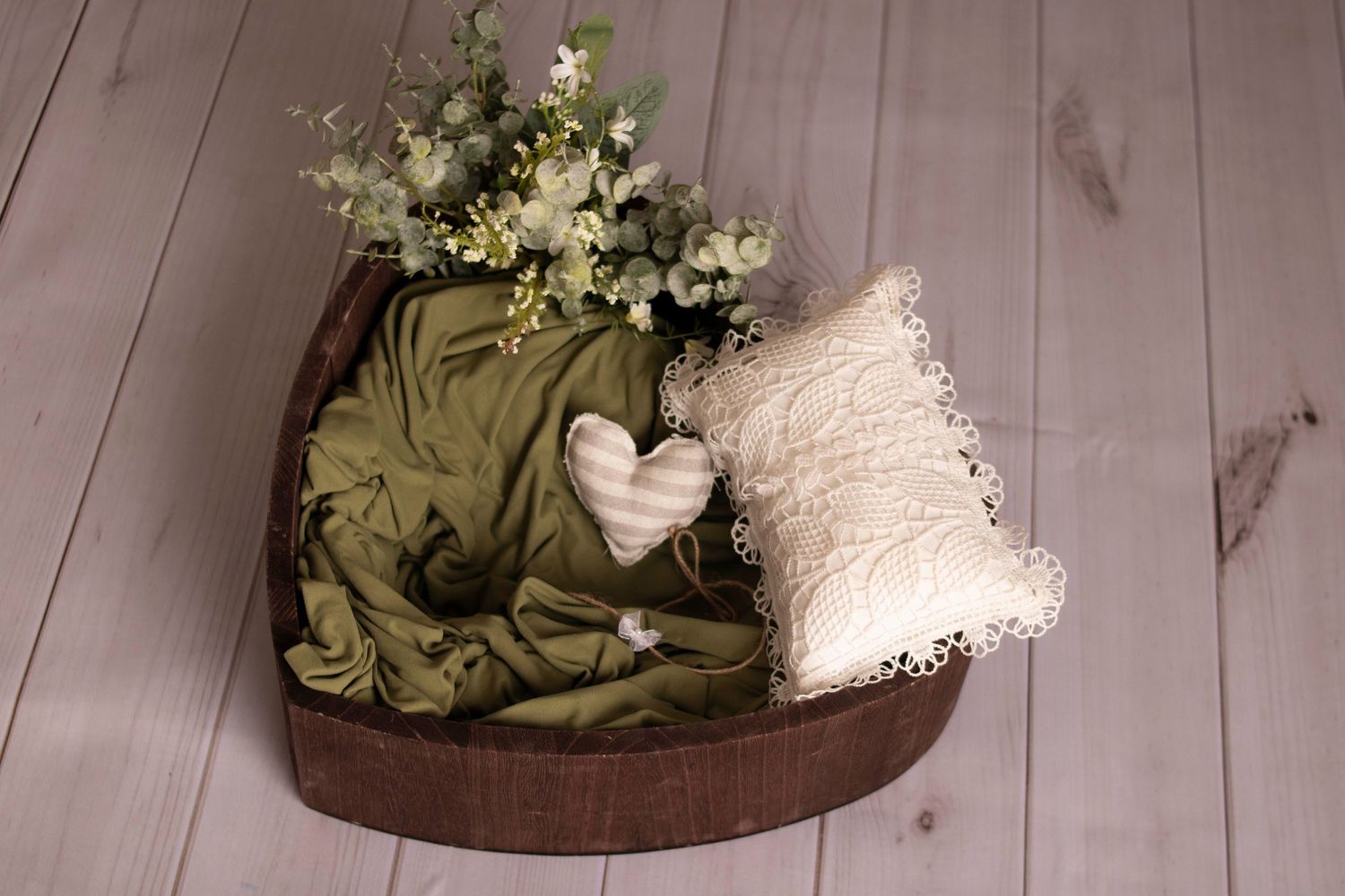 Decorative wooden bowl with green fabric, white flowers and lace pillow.