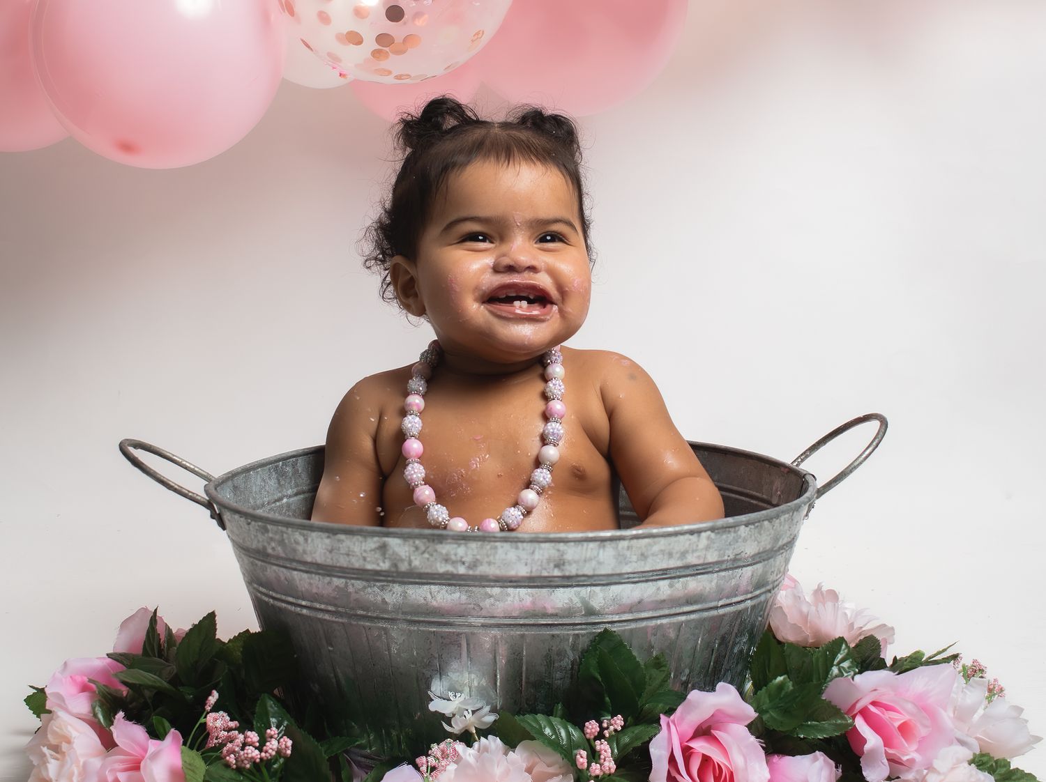 Festive photo in metal tub surrounded by pink flowers and balloons.