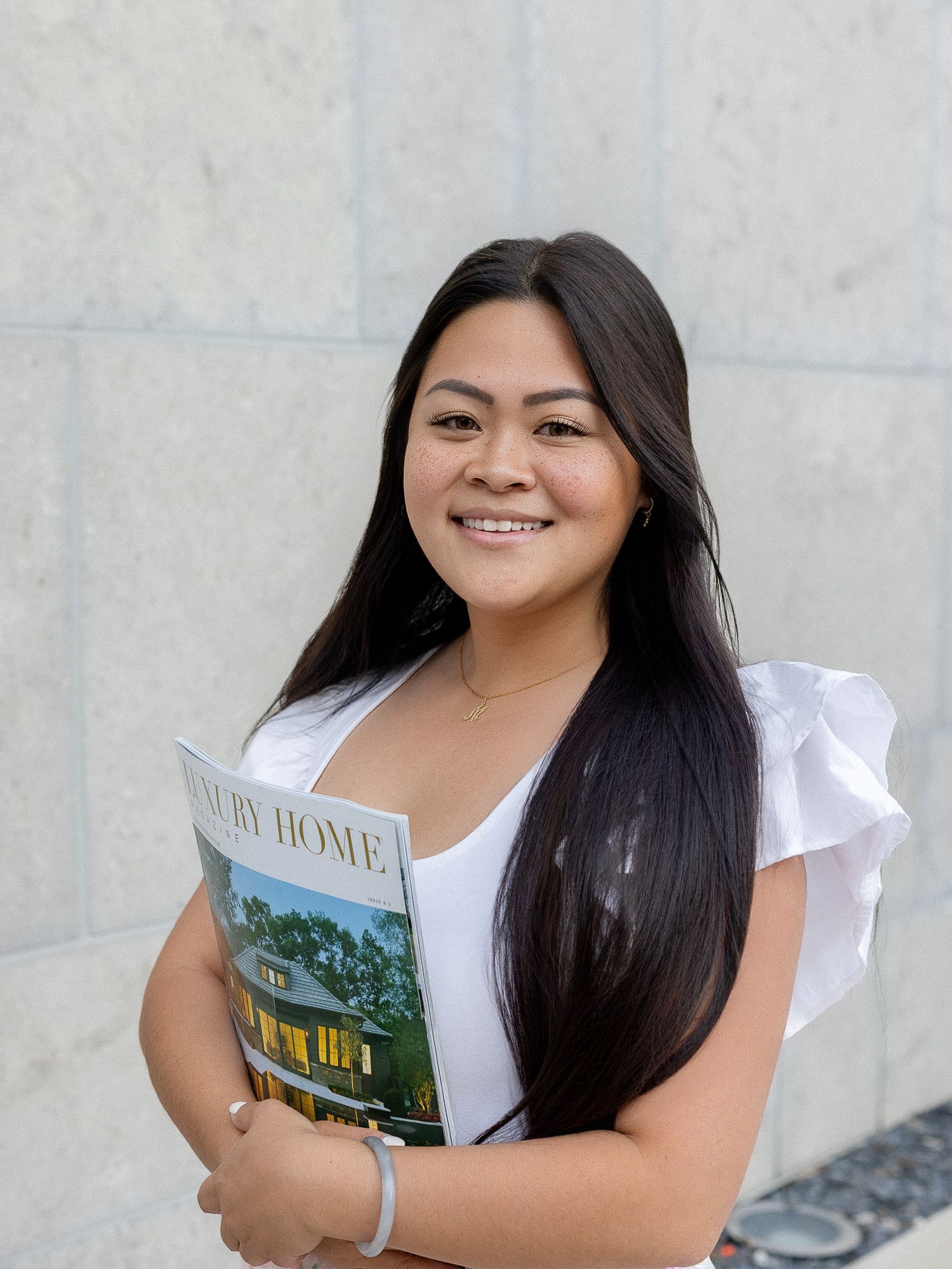 Happy student in white collared shirt holds book against white wall background.