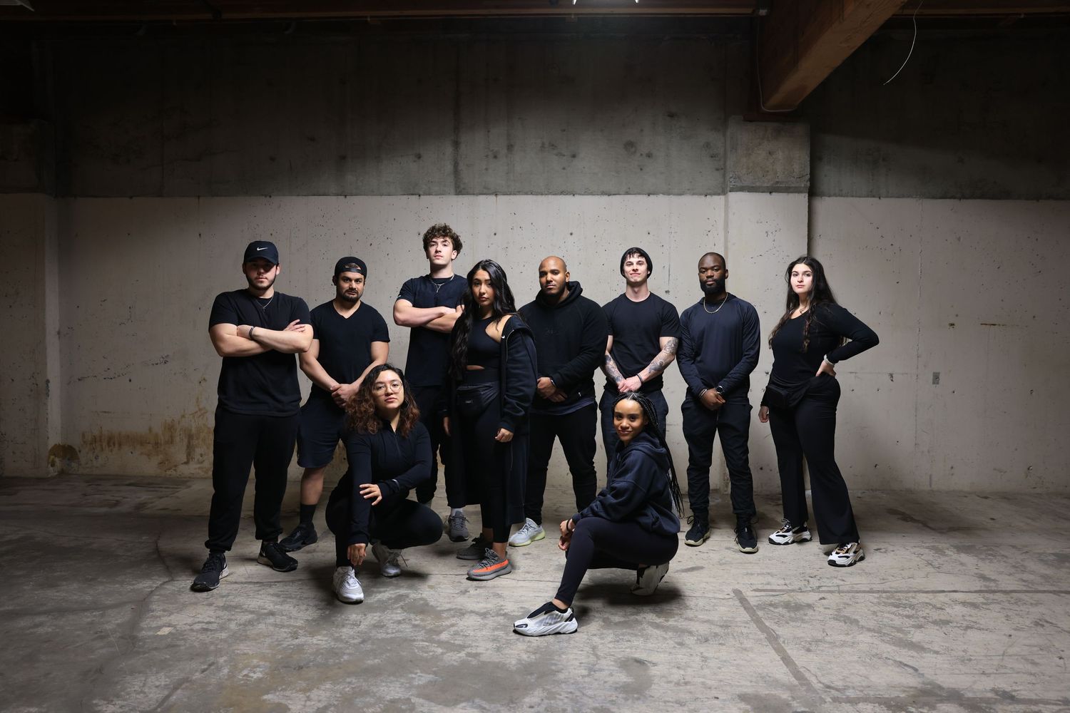 Group photo of people wearing all black outfits standing together in an industrial space.