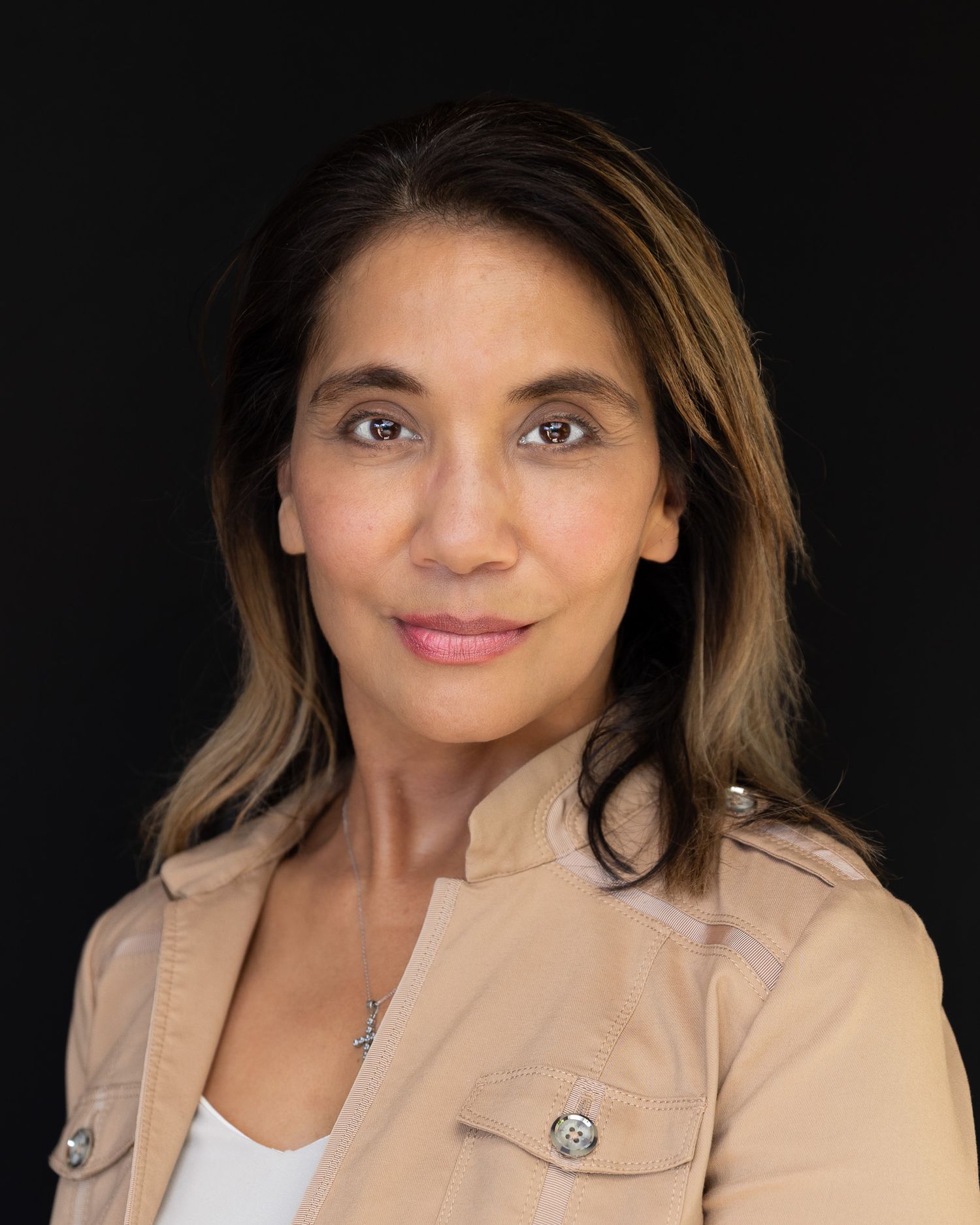 Professional headshot portrait with light tan blazer against dark background.