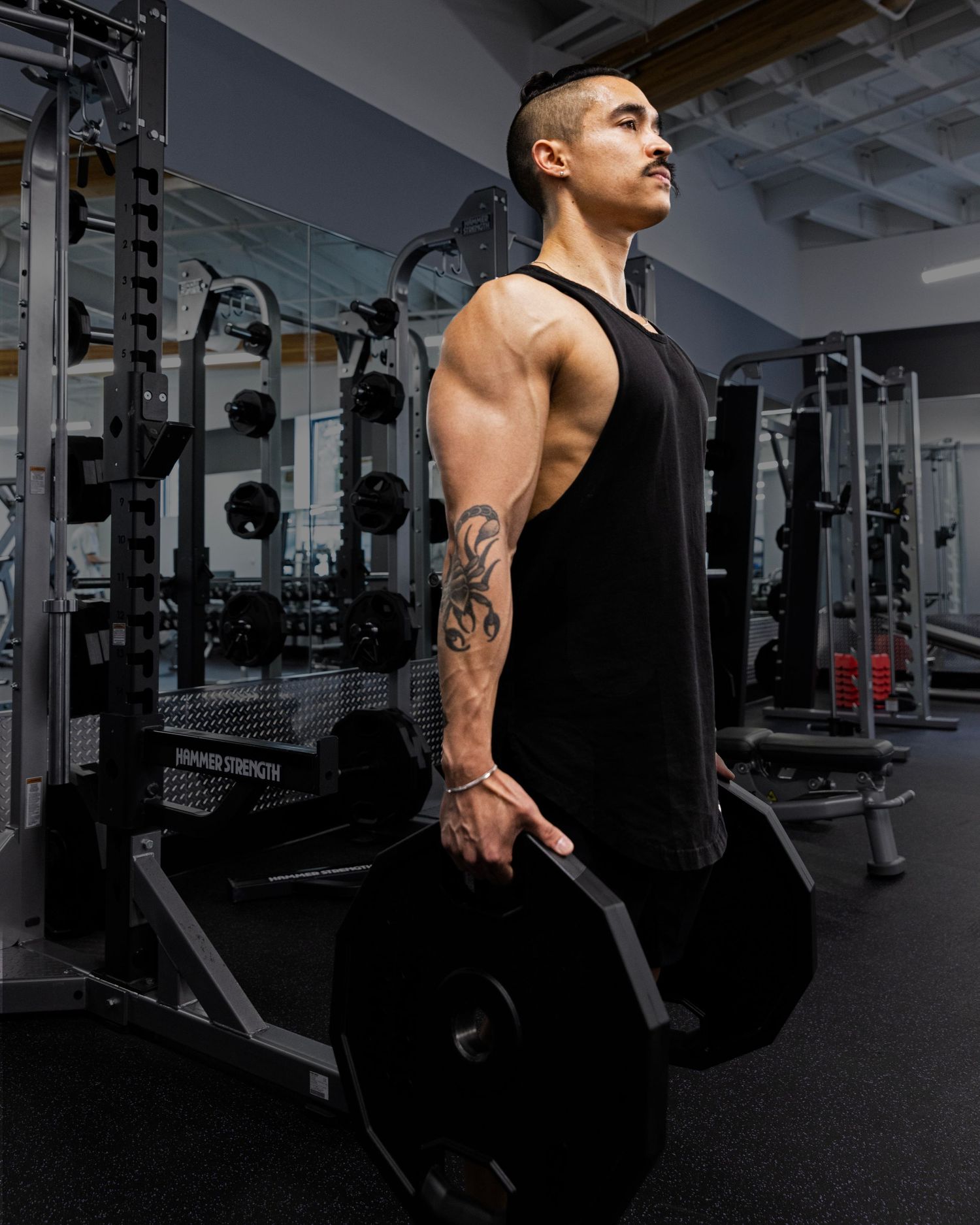 Athletic person in a black tank top performing dips exercise on parallel bars in a modern gym setting.