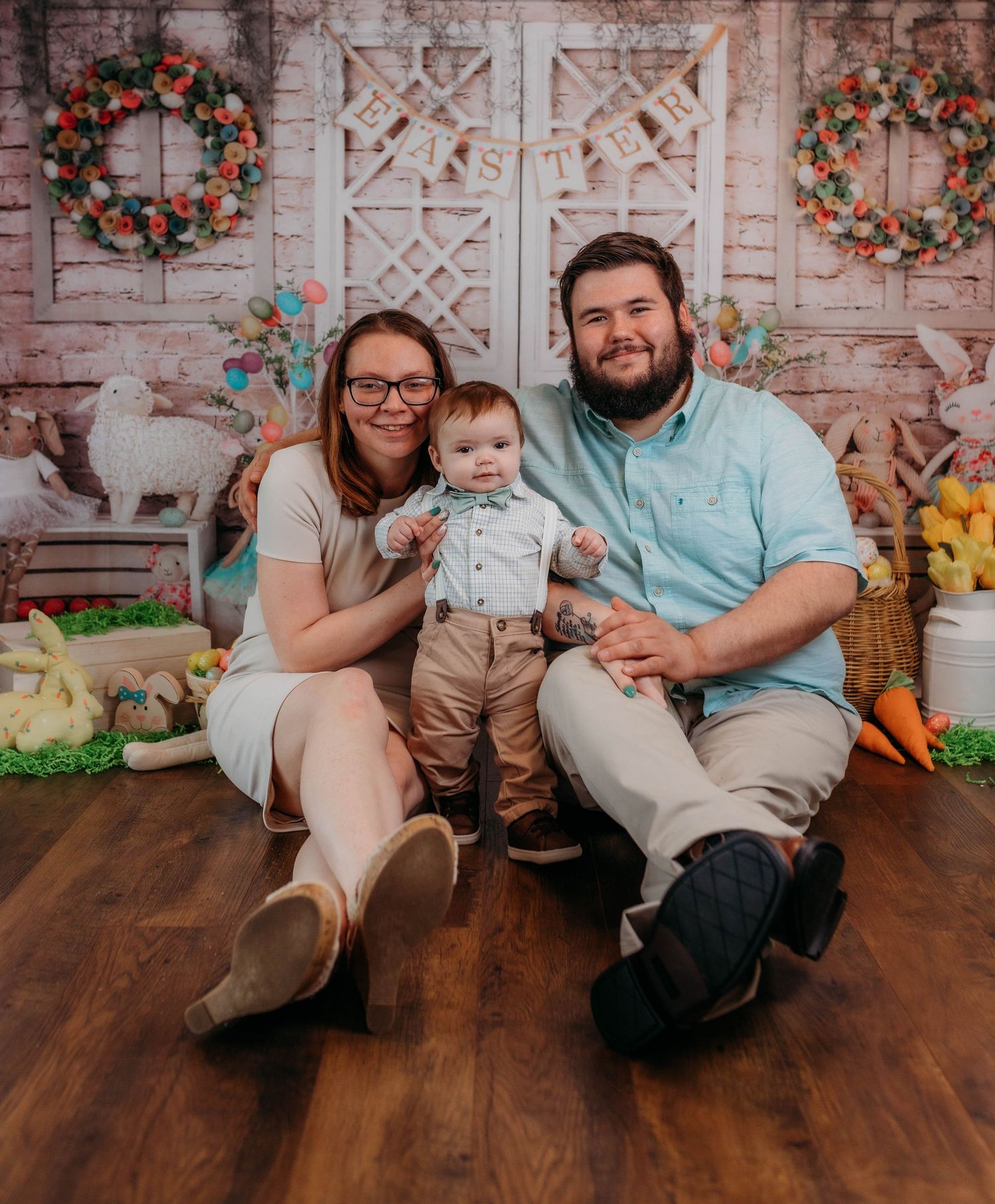 Family portrait with spring decorations and floral wreaths on rustic backdrop.