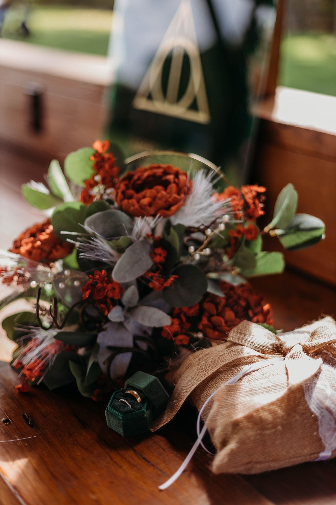 Autumn wedding decor featuring dark florals and eucalyptus on wooden surface.