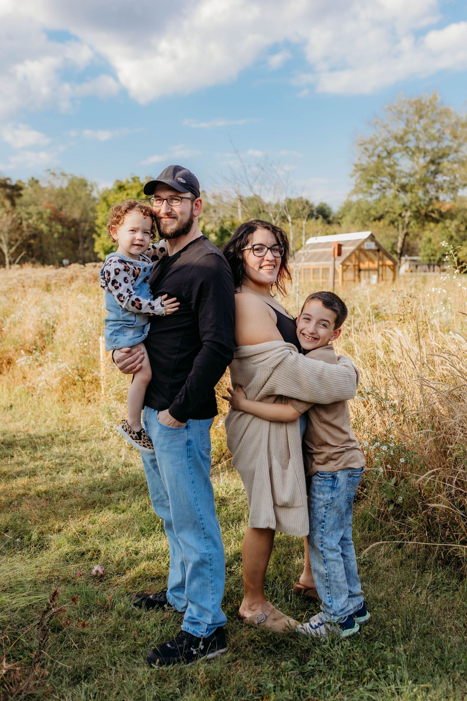 Family sharing playful moments together in rustic outdoor setting during golden hour.