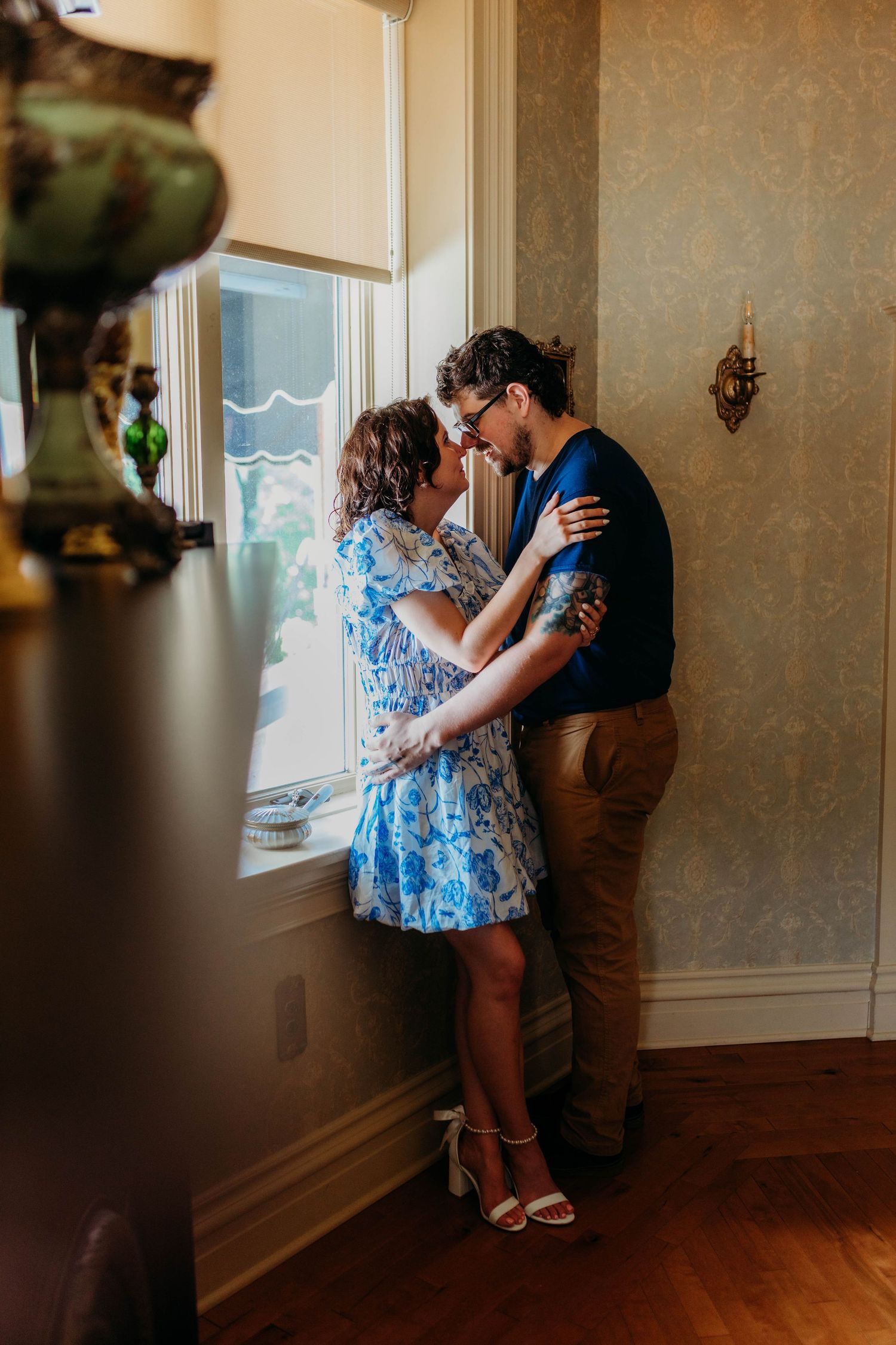 Couple embracing by window in romantic indoor setting.