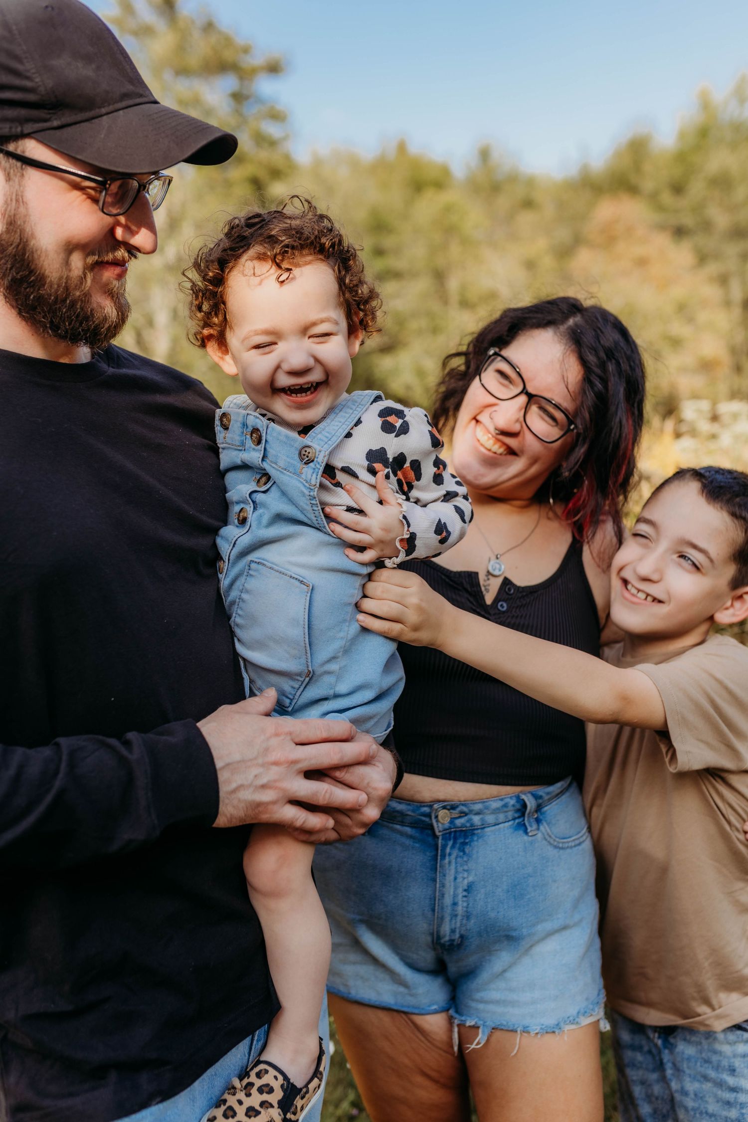 Joyful family embracing and laughing together outdoors on sunny autumn day.