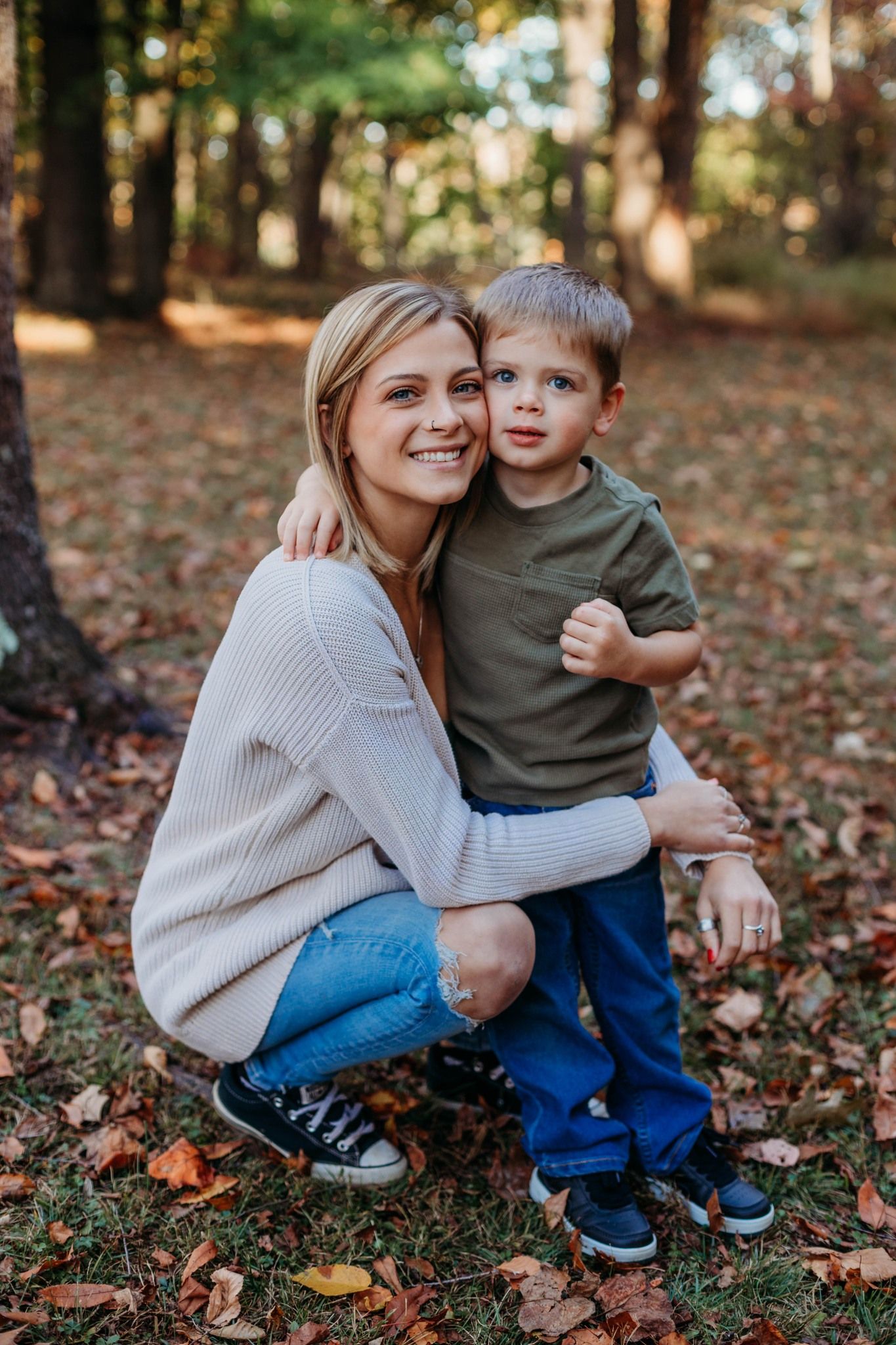 Sweet autumn photoshoot with a cream sweater and blue jeans against fallen leaves.