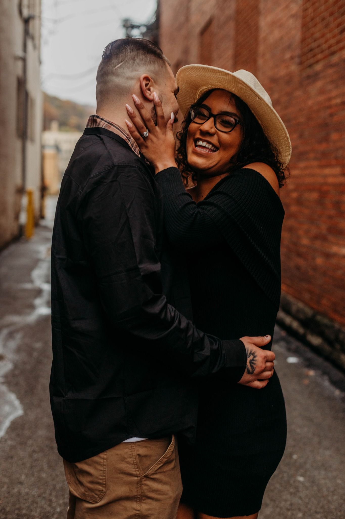 Romantic sequence of embraces against a brick wall background in an urban alley.